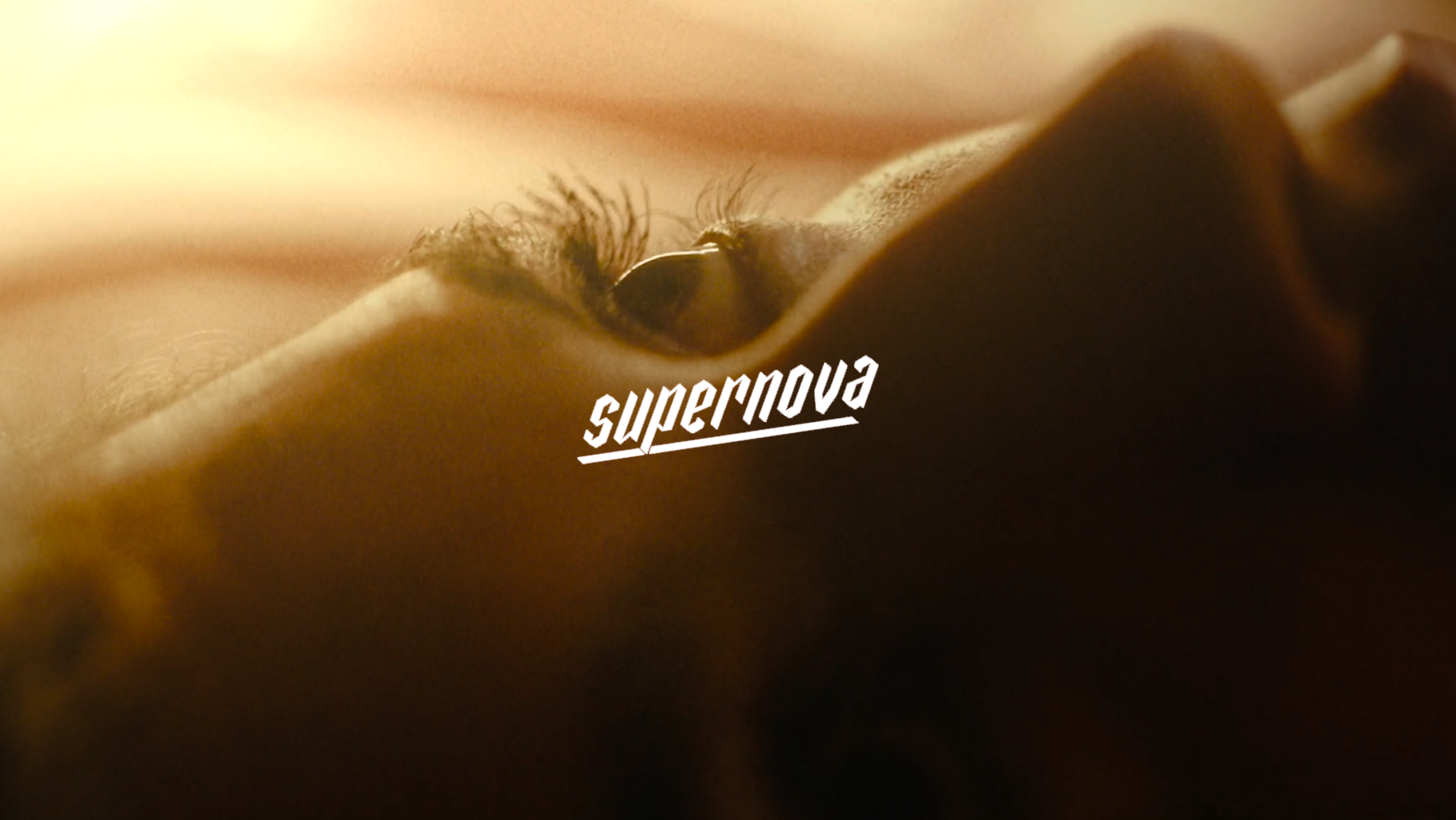 Close-up of a person's eye partially covered by a finger, with the word 'supernova' overlayed in white text.