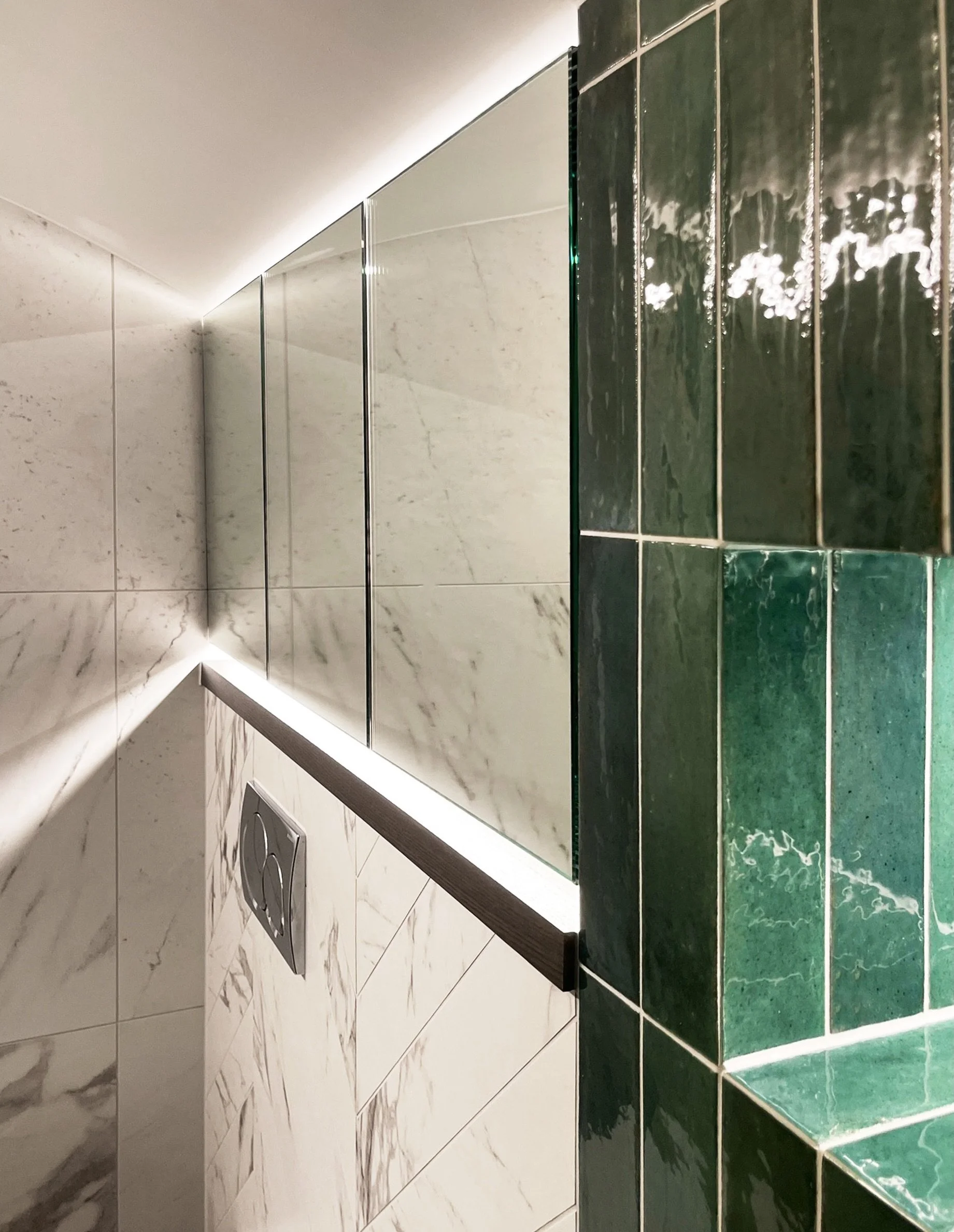 The detail that makes this corner sing is what you don&rsquo;t immediately notice.
A concealed light runs along the perimeter of the ceiling, washing the arch and marble walls in soft light. Light within the niche catches the irregular surface of the