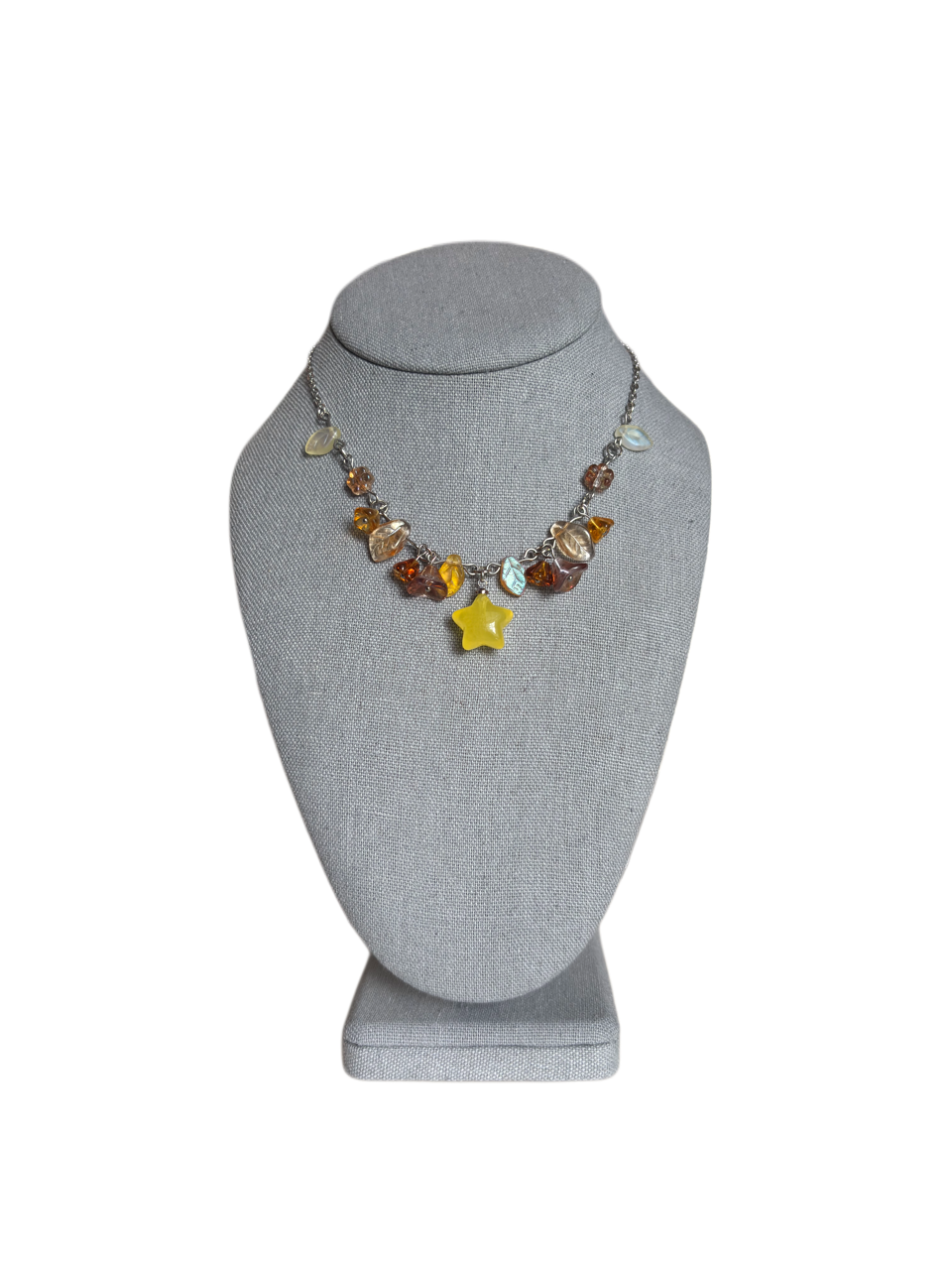 Golden Petal necklace with yellow star, warm amber and yellow glass charms, and translucent leaves on gray bust