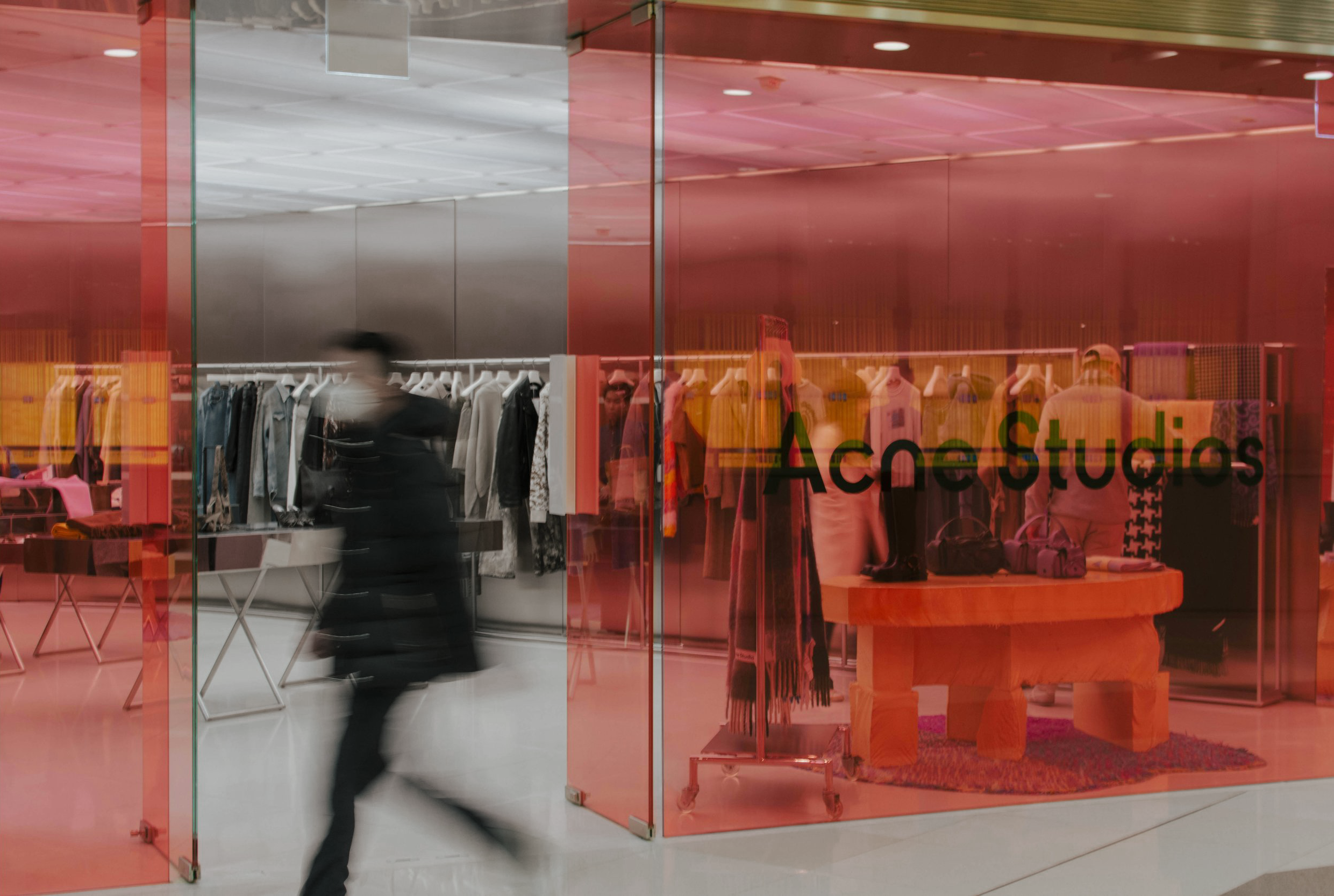 Interior view of a clothing store with clothing racks and a display table, seen through a glass storefront with the store name written on it. This image represents our capability to conduct shop-alongs for our customers.