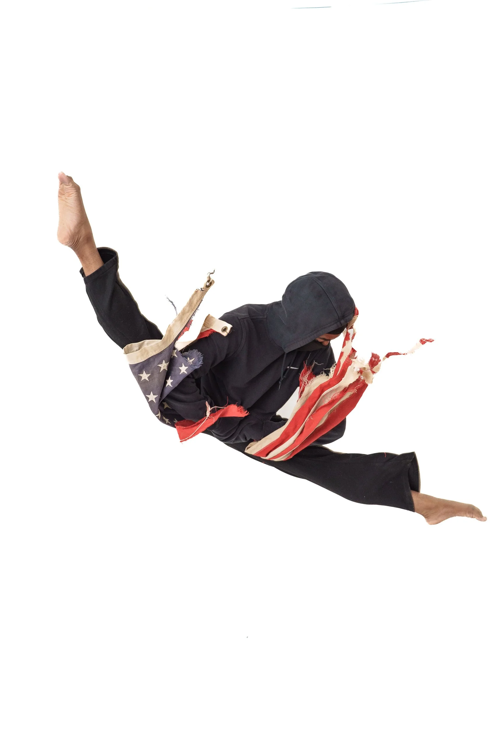 A young black male wearing a hoodie and black pants performing an explosive split leap with an American flag design on the clothing, against a white background for Aquilah Ohemeng professionally known as "KHILA"'s new project honoring Tupac Shakur