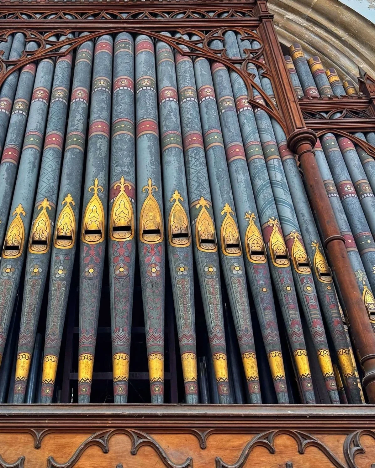 Close-up of an old pipe organ with decorated pipes and wooden carvings.