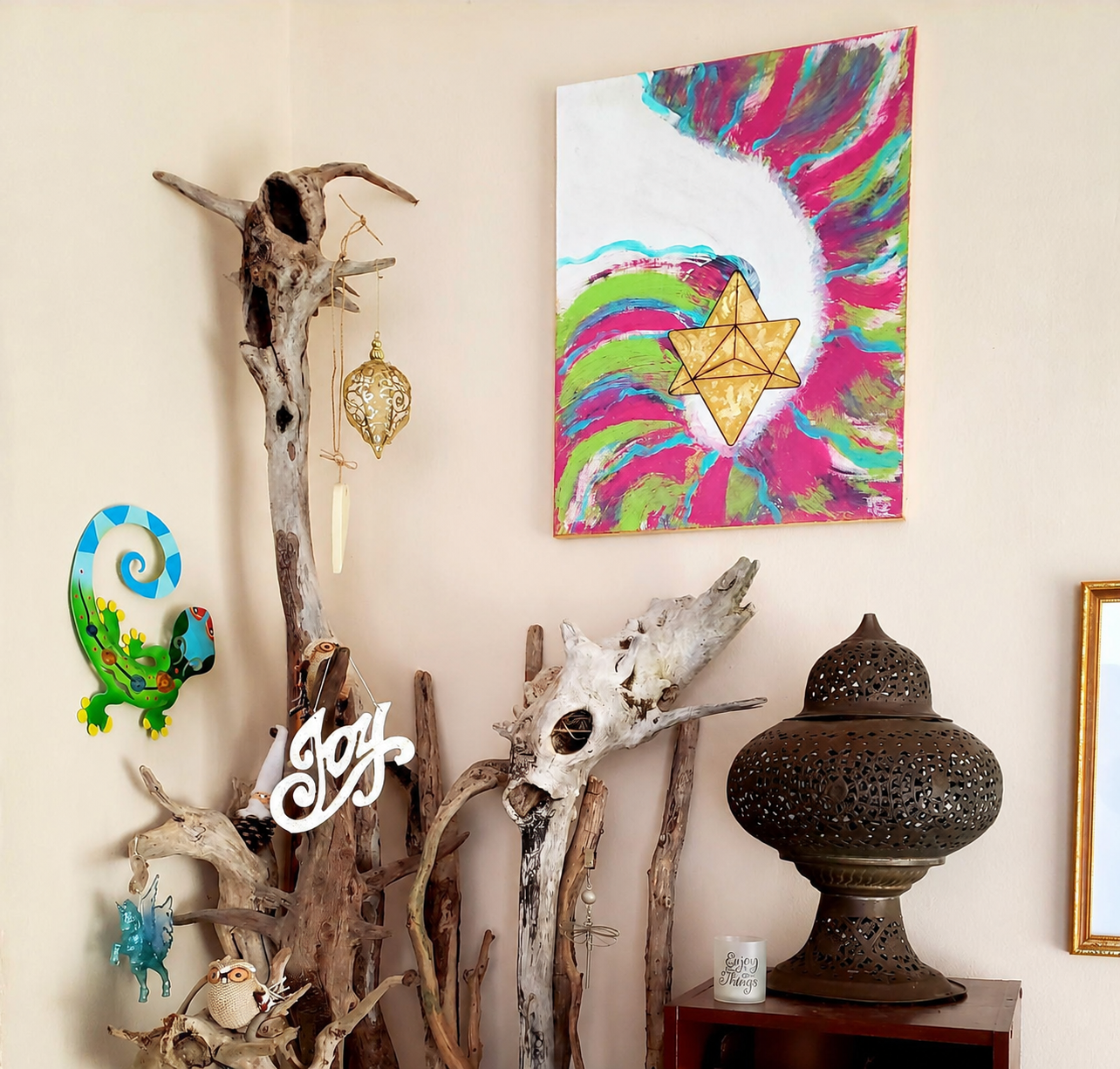 A corner inside The Elemental Lantern with driftwood, symbolic art, a lantern, and one of DeAn’Na’s paintings, offering a glimpse into the creative presence of the space.