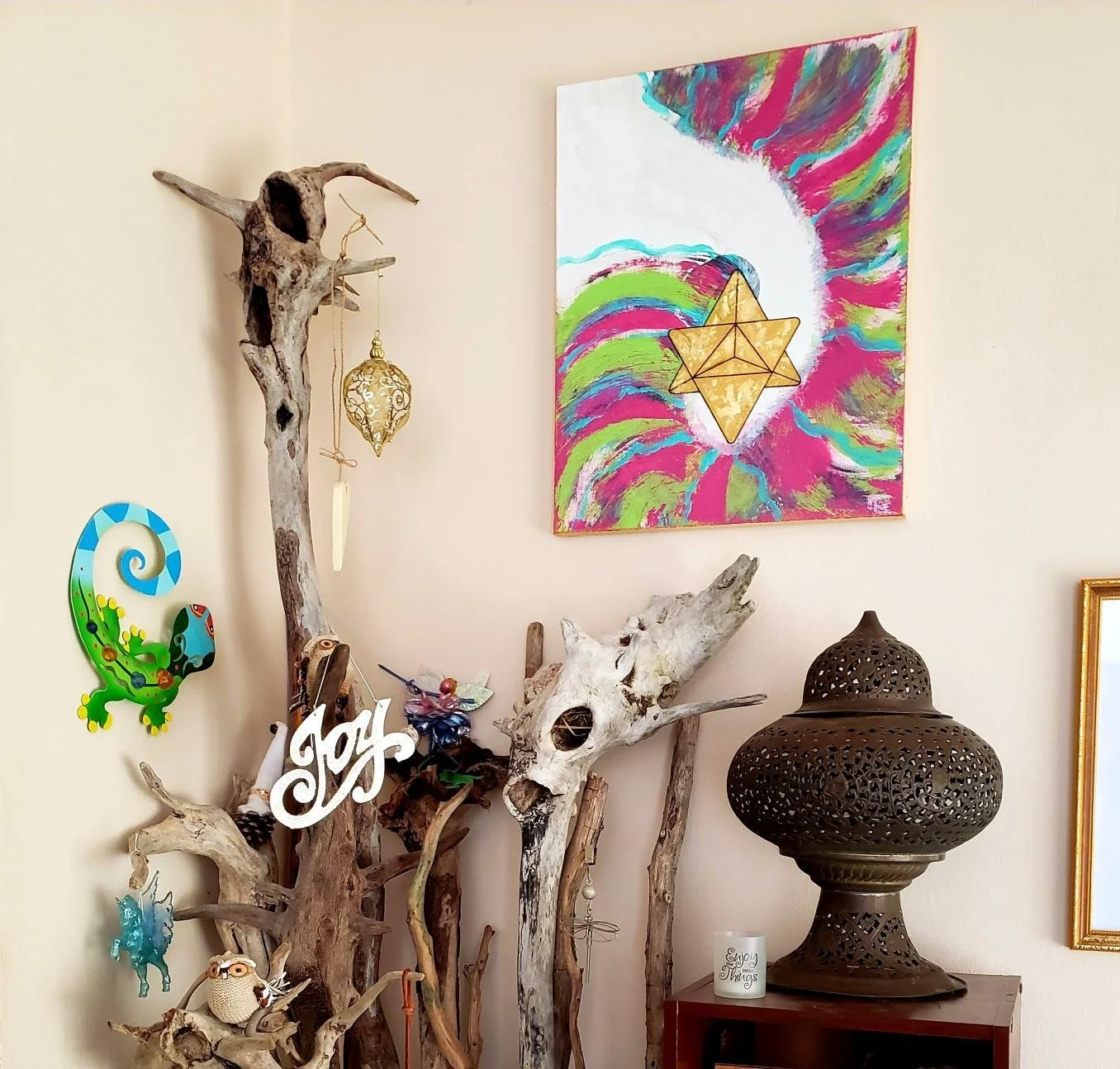 A corner inside The Elemental Lantern with driftwood, symbolic art, a lantern, and one of DeAn’Na’s paintings, offering a glimpse into the creative presence of the space.