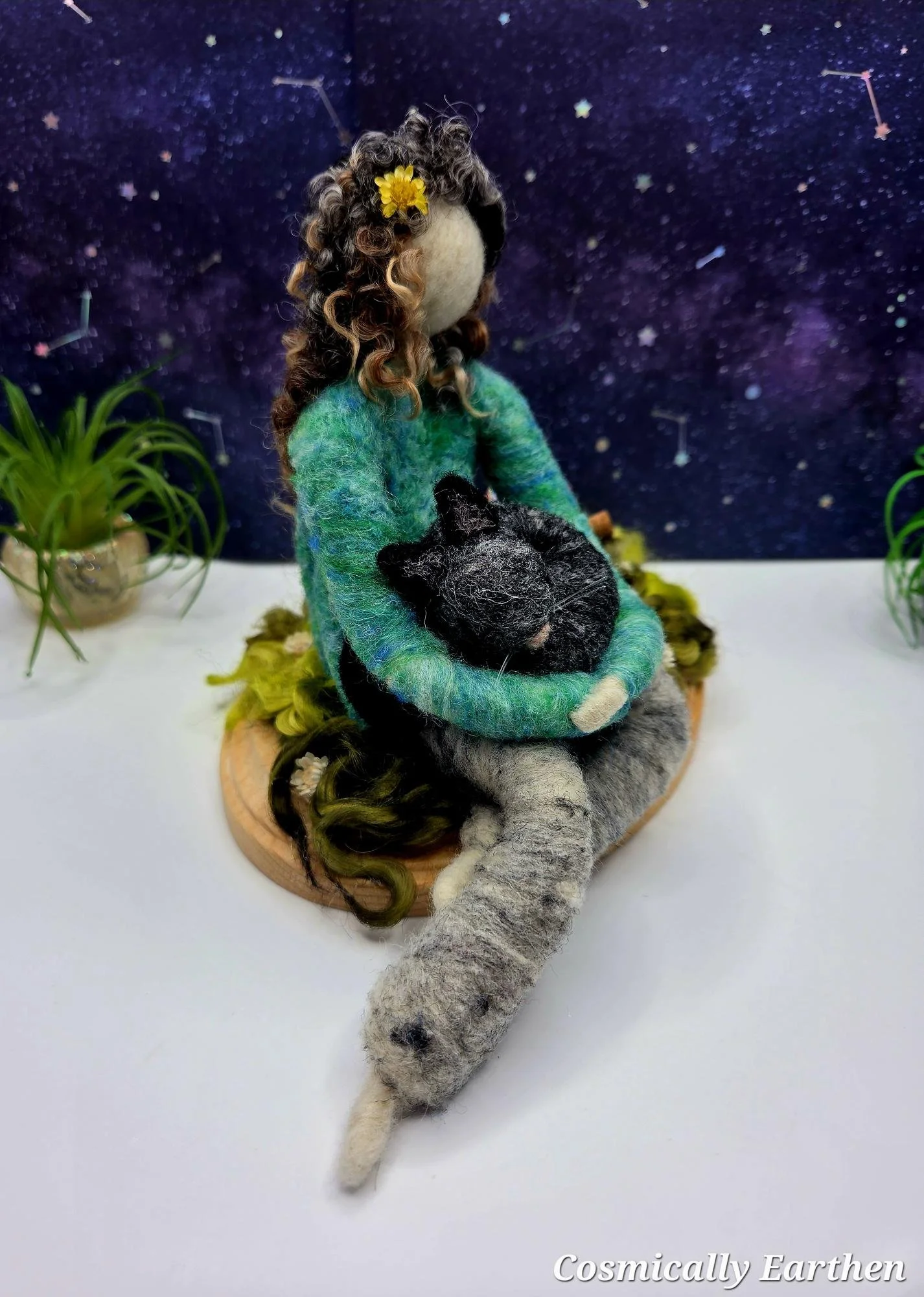 Handmade needle-felted companion figure holding a black cat, seated on a grassy base with natural elements, created as a custom pet keepsake.