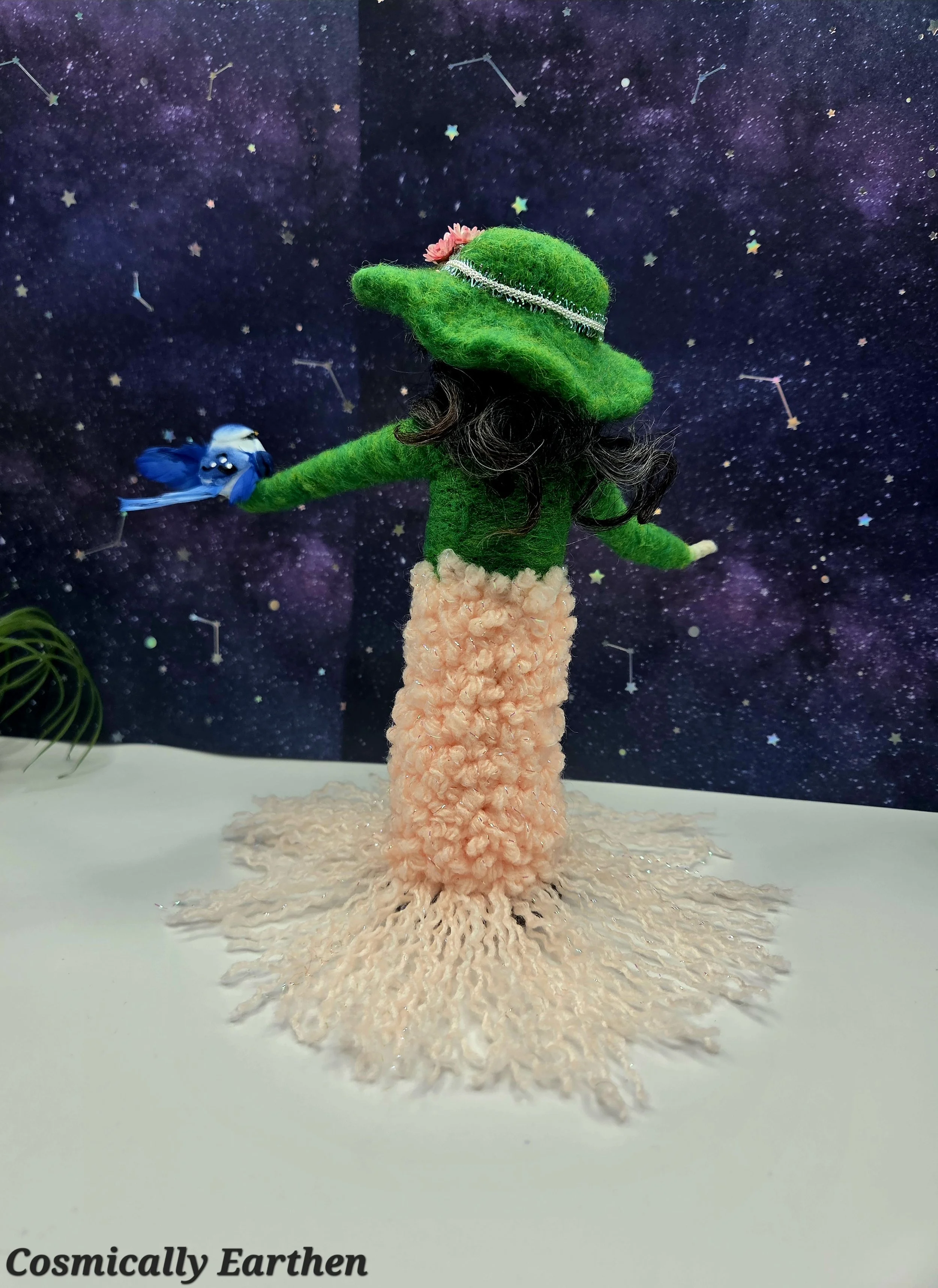 Back view of needle felted green doll Liora with layered wool fibers and natural textures, displayed on a wood base as a one-of-a-kind handmade art doll