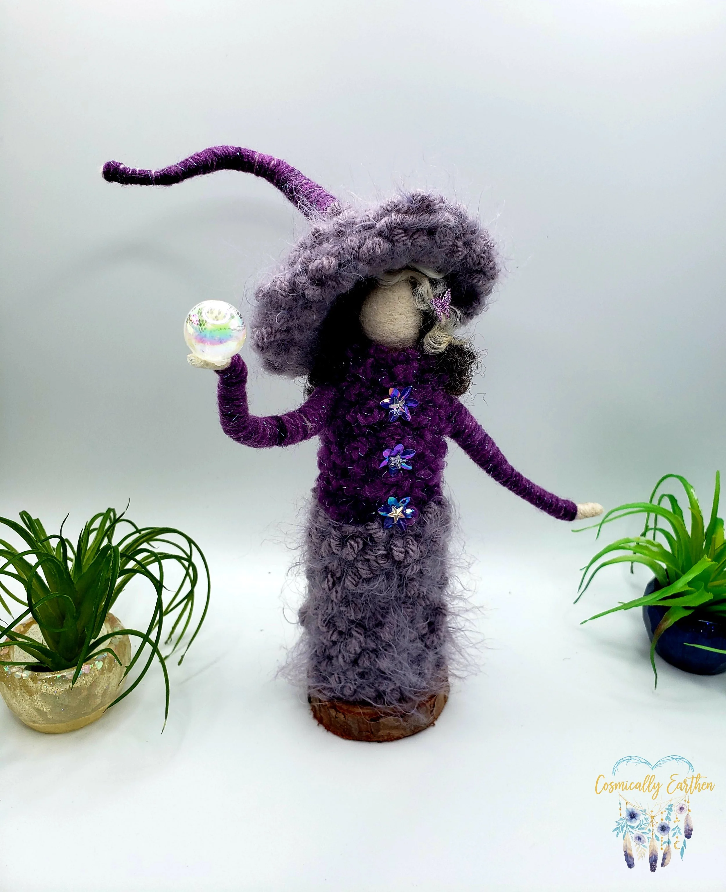 Handmade needle felted purple doll named Velora holding a small orb, featuring textured wool clothing and pointed hat, mounted on a wood base as a one-of-a-kind fiber art figure