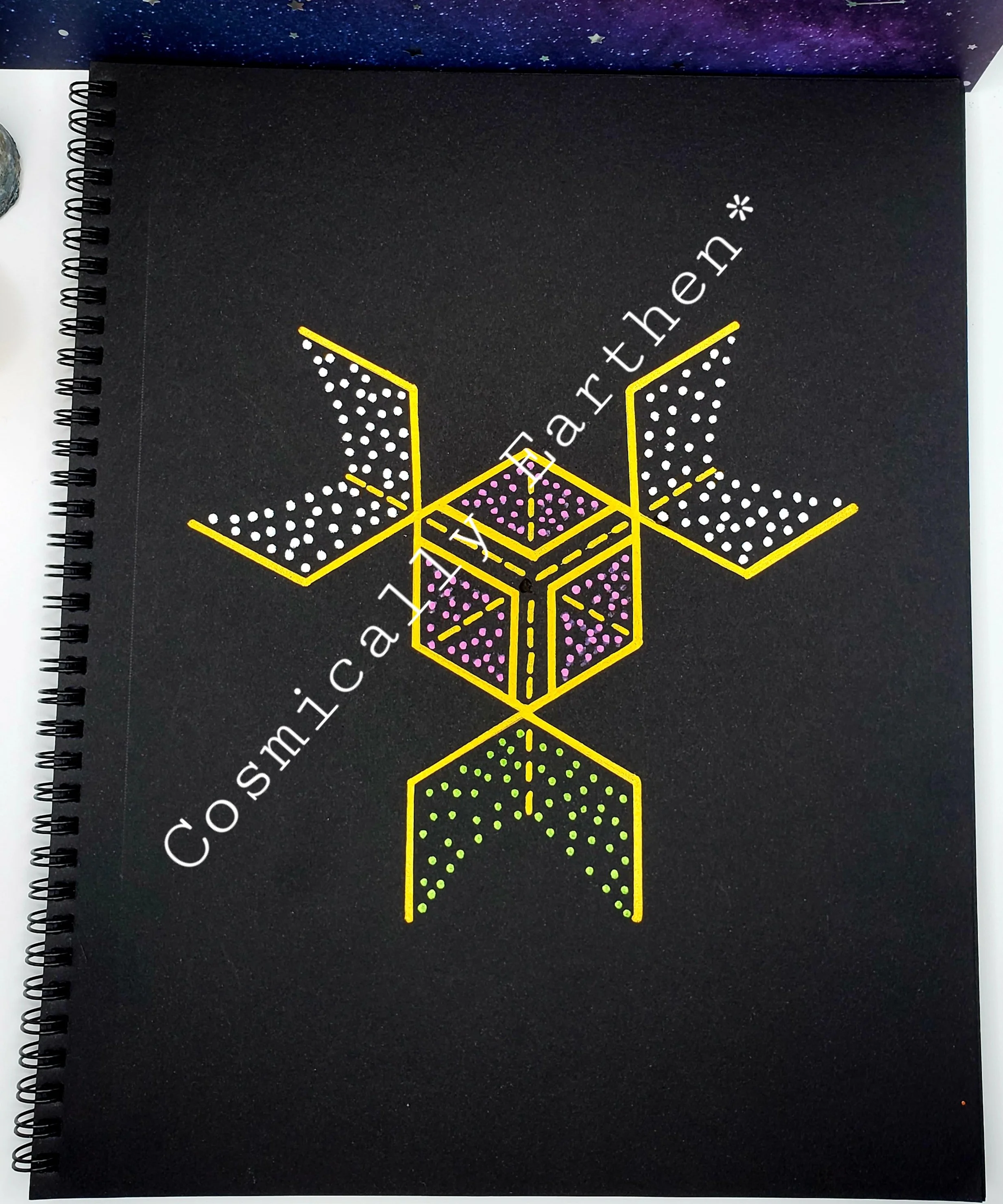 Cover of a black spiral notebook featuring a geometric, digital-style design with three gold-outlined cubes, dotted with purple and green accents, and white diagonal text reading 'Cosmica Art the'.