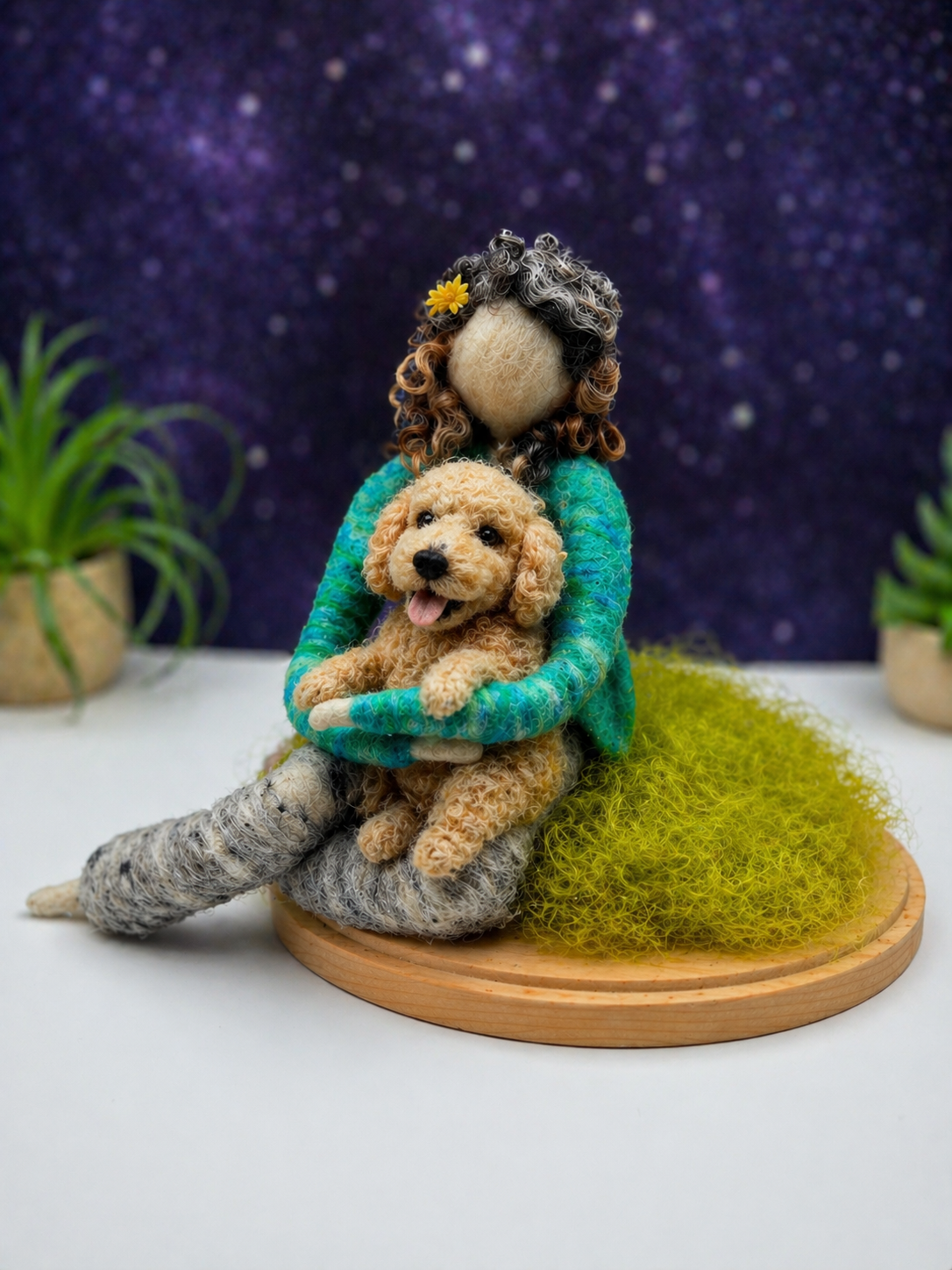 Custom needle-felted companion figure holding a small dog, seated on a natural grassy base, designed as a meaningful pet keepsake.
