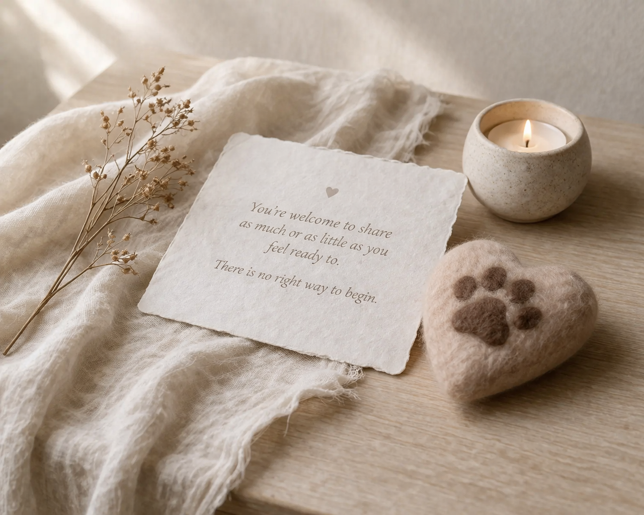 handmade pet memorial keepsake with felted heart and paw print in soft still life setting with candle and natural light