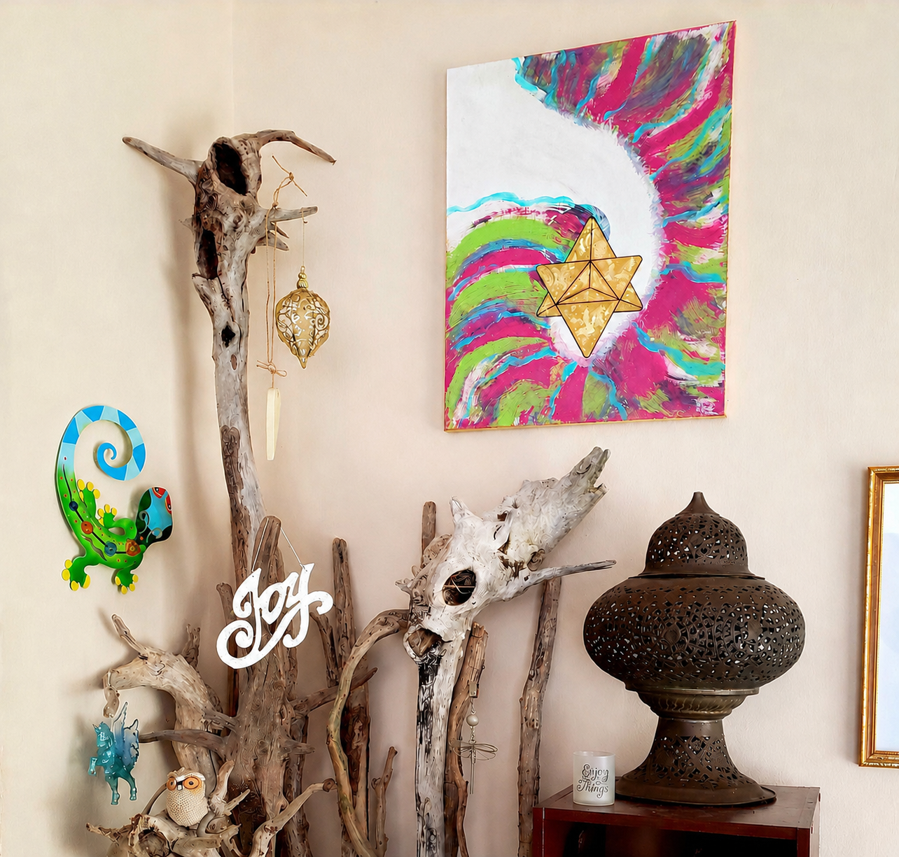 A corner inside The Elemental Lantern with driftwood, symbolic art, a lantern, and one of DeAn’Na’s paintings, offering a glimpse into the creative presence of the space.
