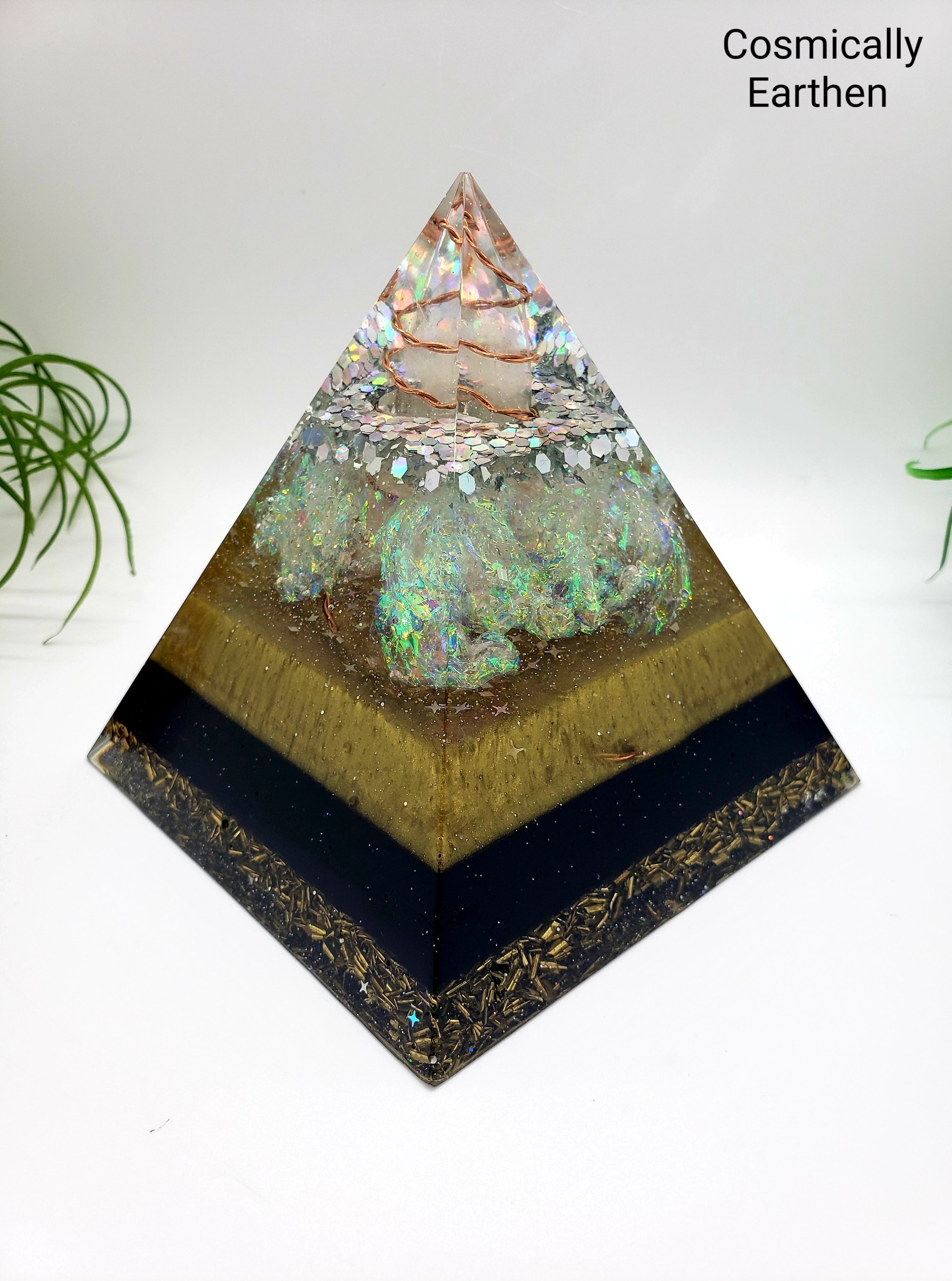 Handmade orgonite pyramid with embedded crystal and resin layers, featuring geometric structure and metallic elements. Decorative energy piece for home, meditation, or display.
