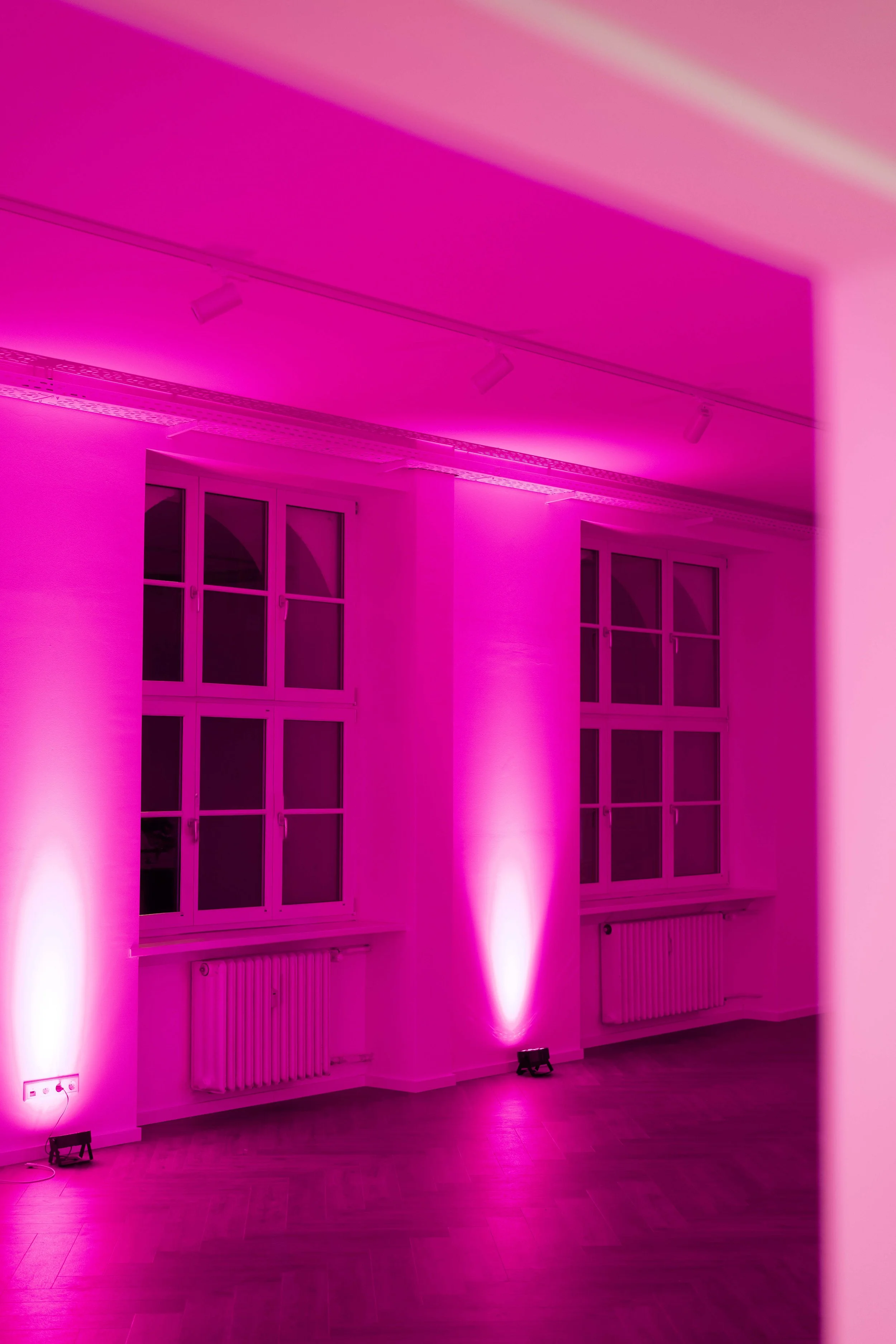 Ein Raum mit großen Fenstern, der mit pinkem Licht beleuchtet ist.
