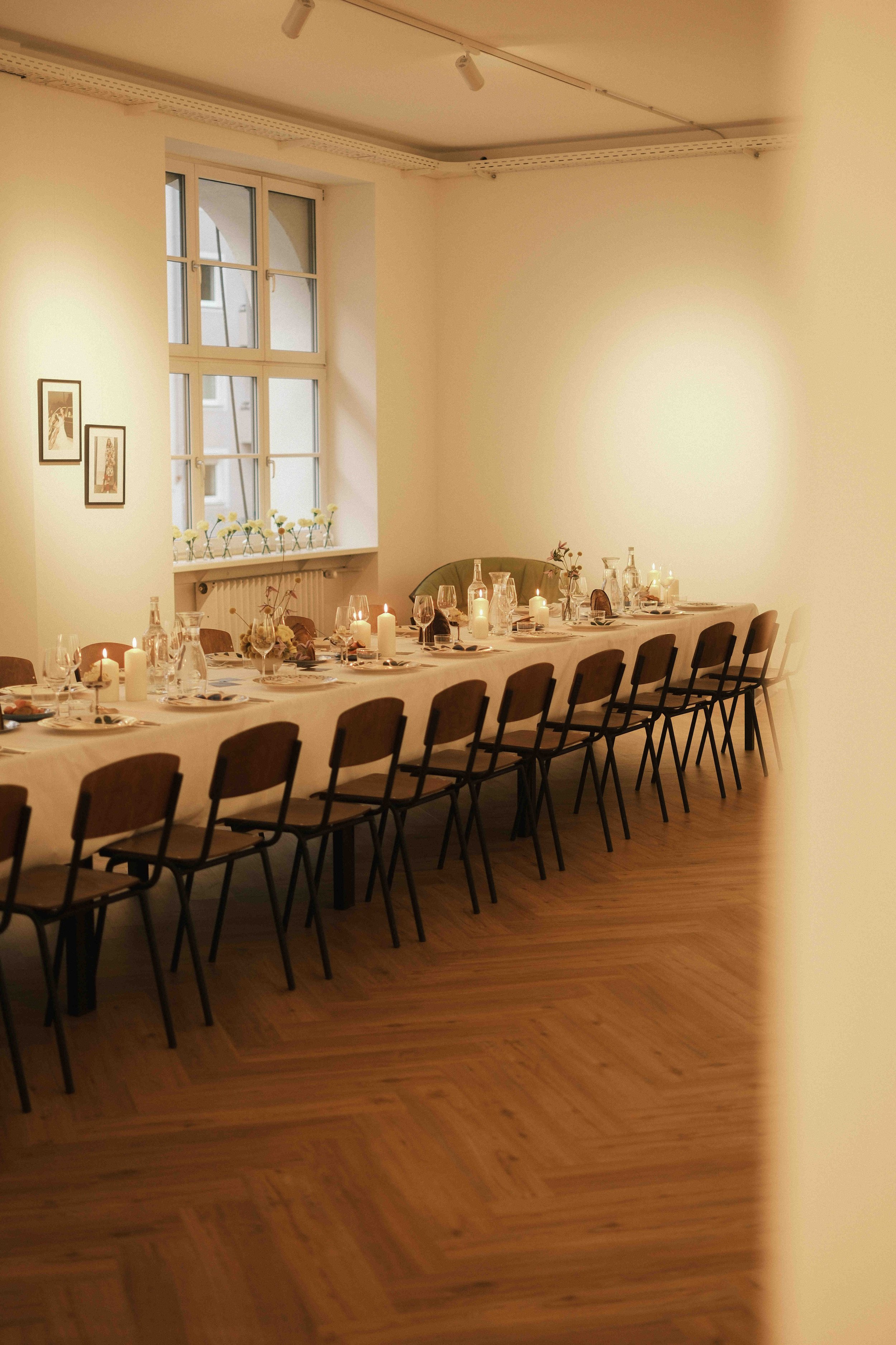 Ein gedeckter Tisch mit Kerzen und Gläsern in einem hell erleuchteten Raum, bereit für eine Veranstaltung.