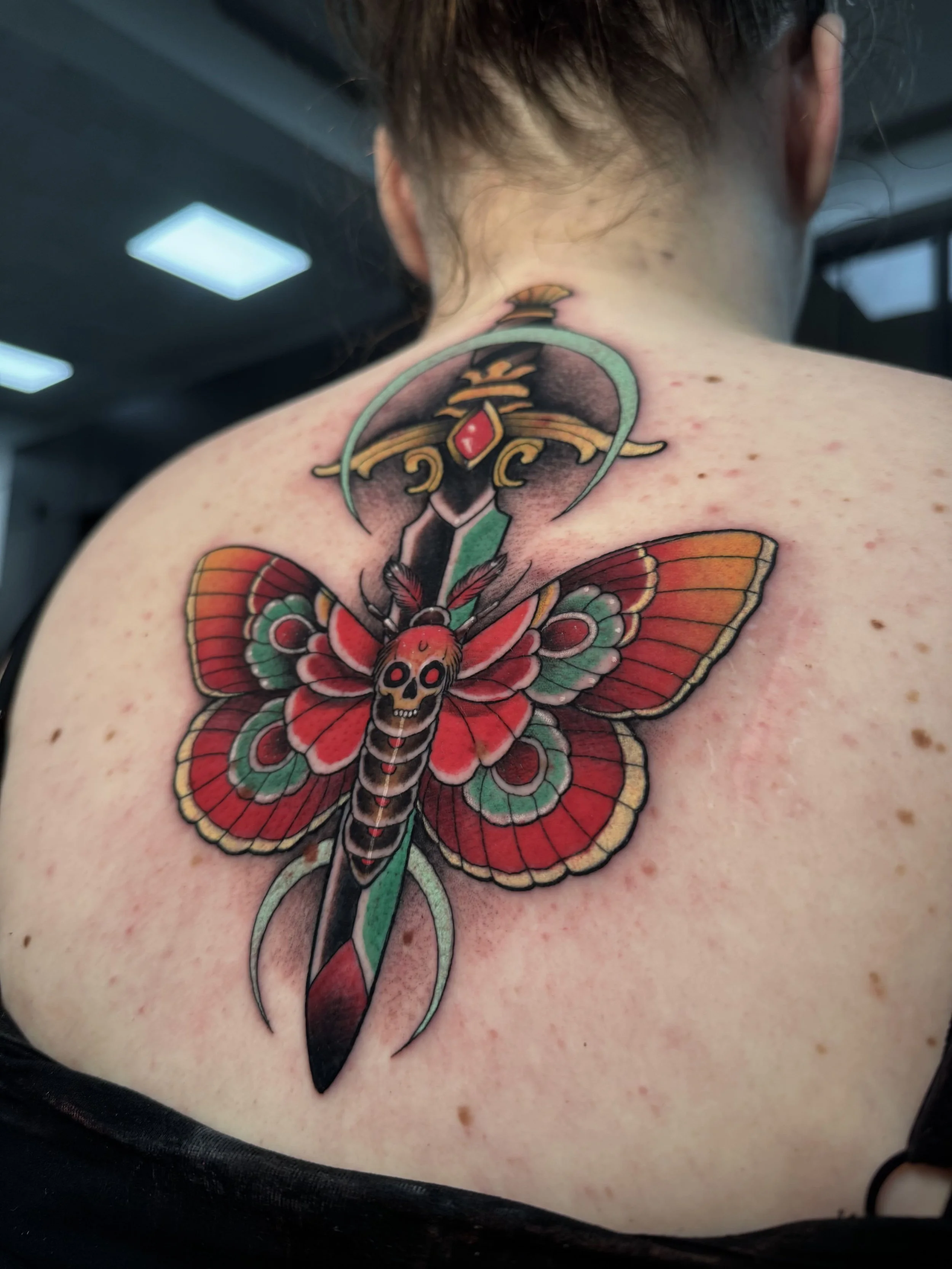 Butterfly dagger tattoo i farver på ryggen lavet af tatovør Bruno Mazallo