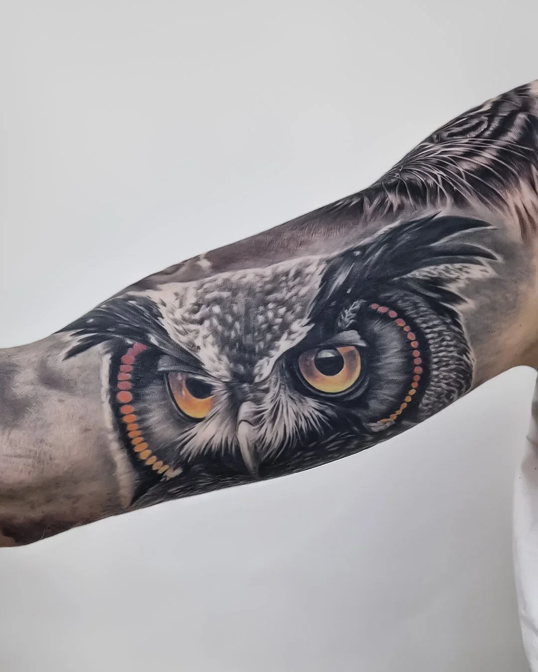 Portræt-tatovering af en flot ugle med splash af farve – detaljeret og farverig tattoo udført hos Lind Studio i Randers