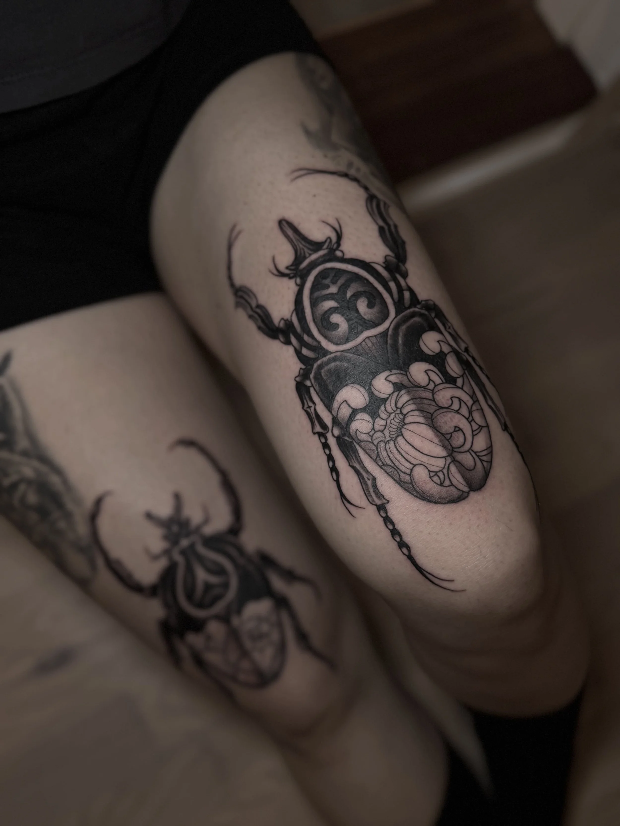 To old school scarabæ tatoveringer i black & grey, én på hvert ben, lavet af tatovør Bruno Mazallo