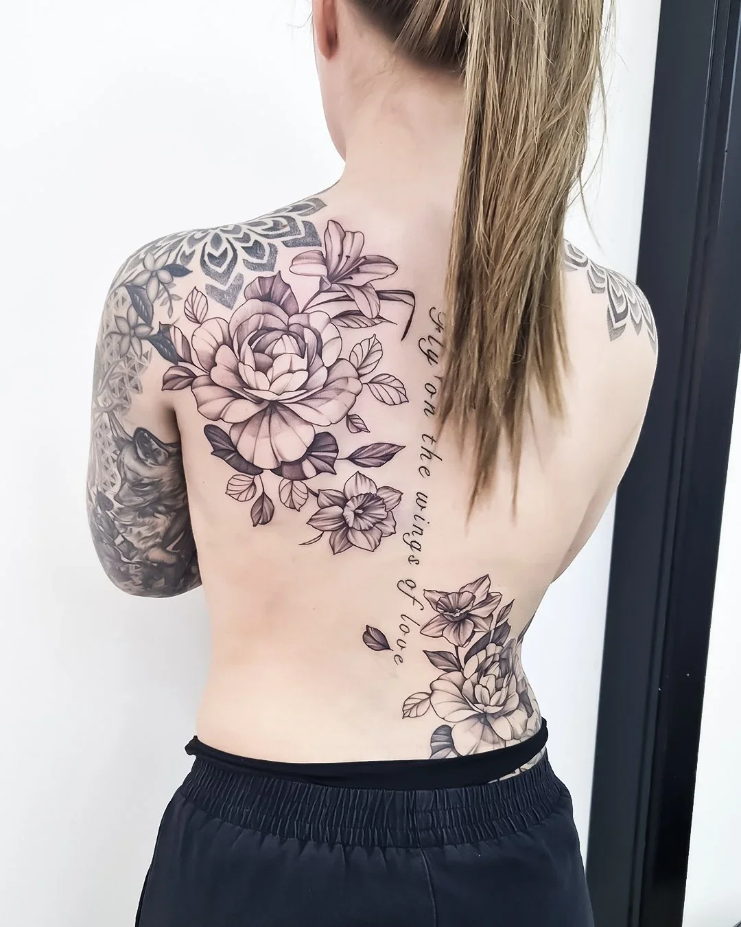 Flot ryg piece med blomster og tekst i fineline-stil – feminin og detaljeret tatovering udført hos Lind Studio i Randers
