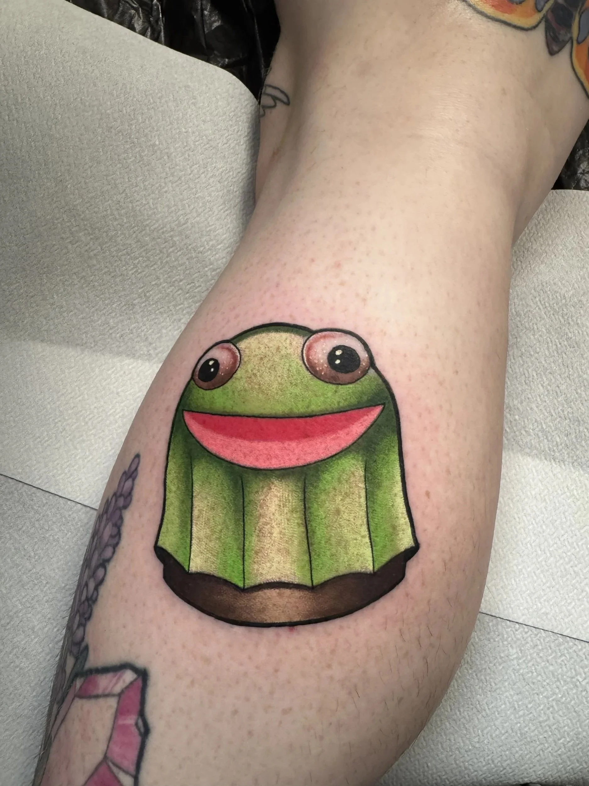 Derpy frog tattoo i humoristisk old school stil lavet af tatovør Bruno Mazallo