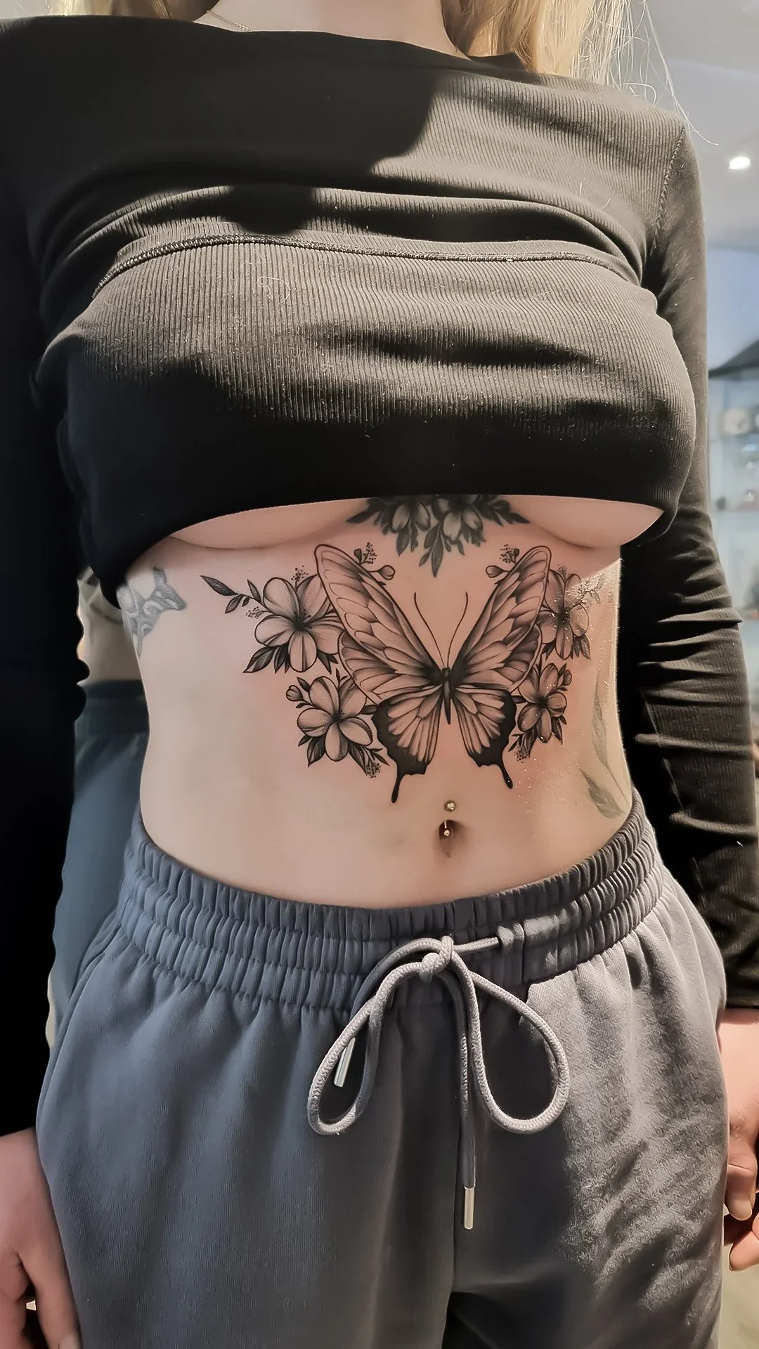 Feminin underboob-tatovering i højeste kvalitet – elegant, detaljeret design udført hos Lind Studio i Randers