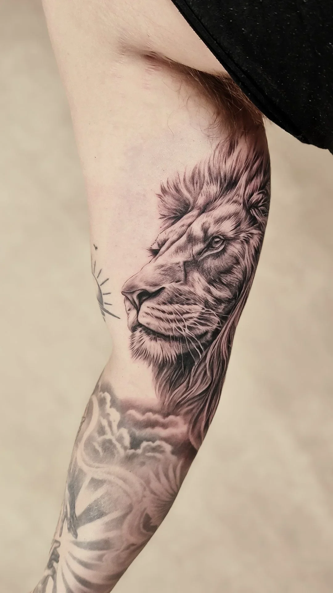 Realistisk løvehoved tatovering i black and grey udført hos Lind Studio i Randers