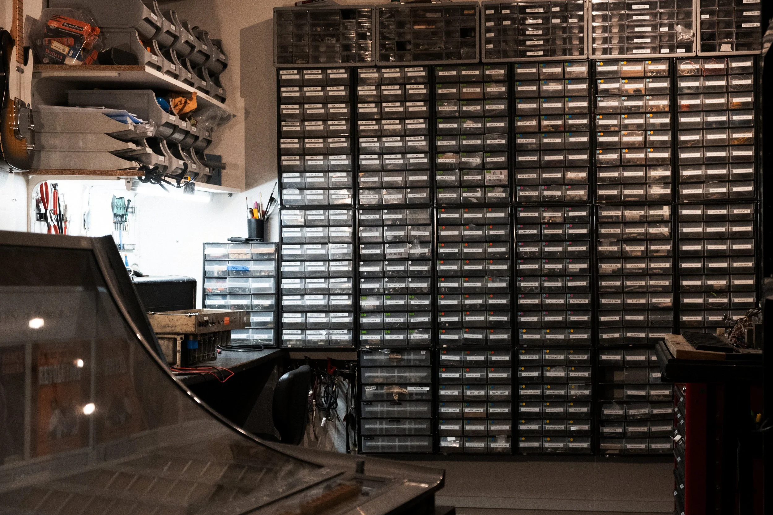 Atelier de réparation d’amplis à lampes avec casiers de composants et châssis d’ampli sur l’établi