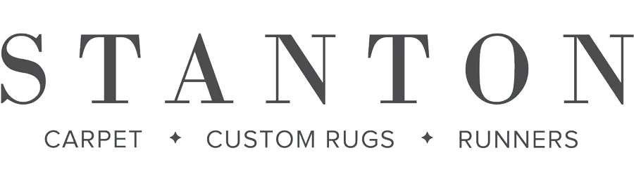 Logo for Stanton Carpet featuring the company name and tagline highlighting carpet, custom rugs, and runners.