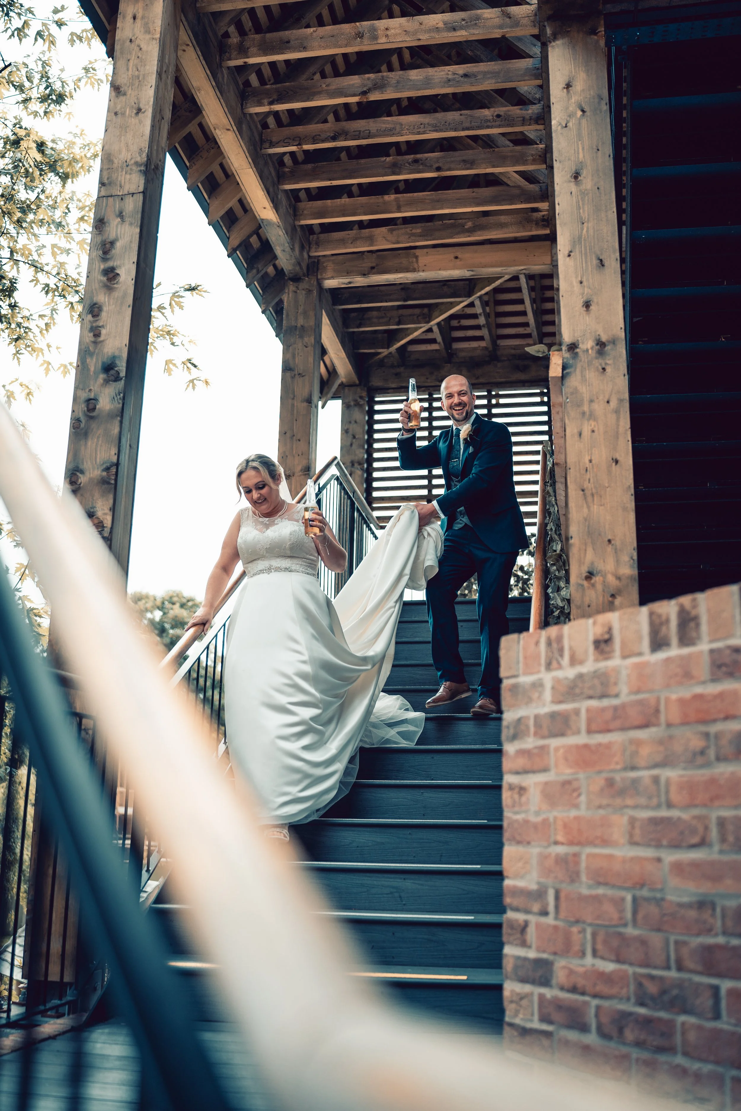 A bride and groom in wedding attire sharing a close moment outdoors with a green, blurred background.