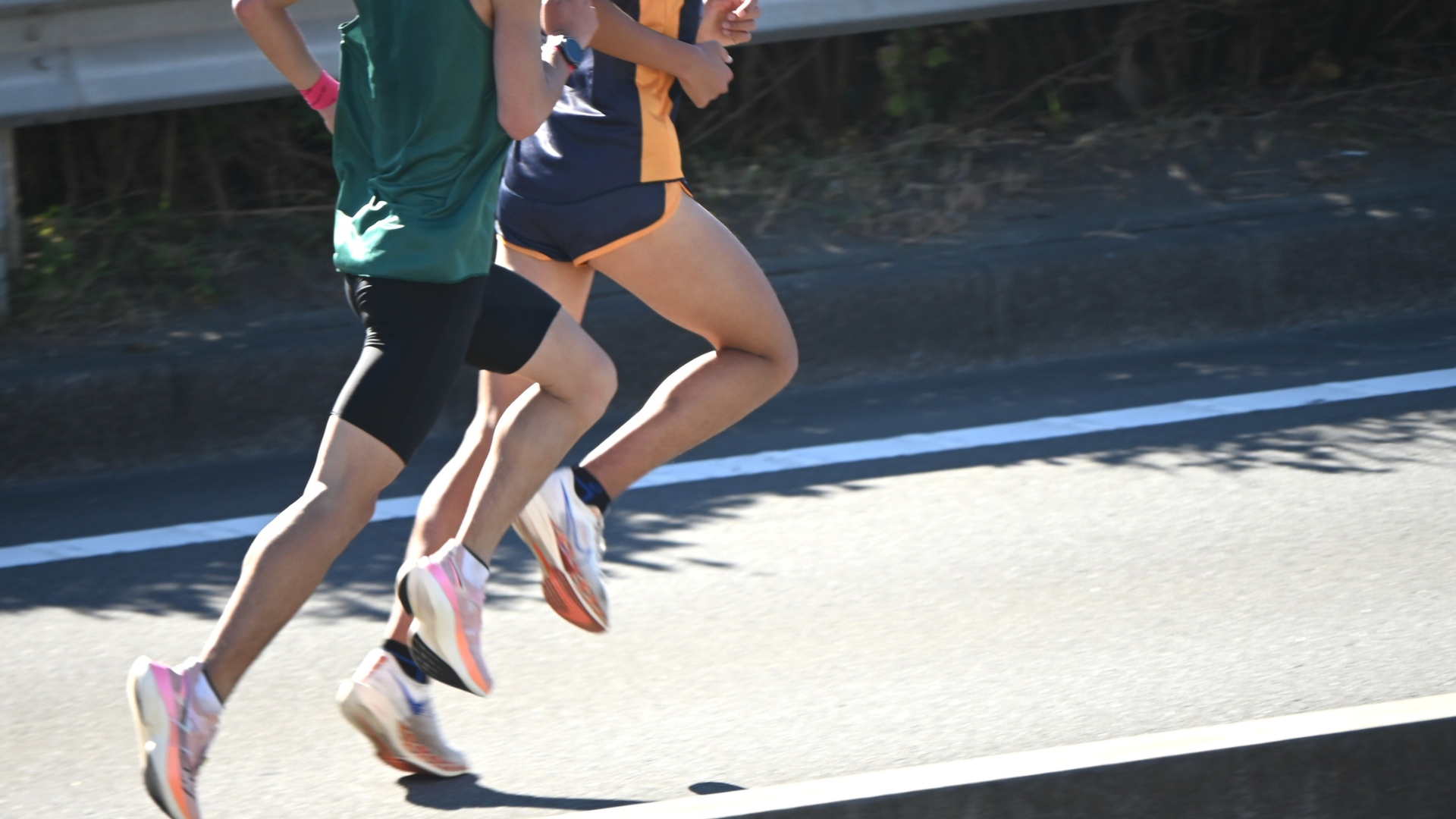 Close-up of two runners' legs and feet running on the road during a race.