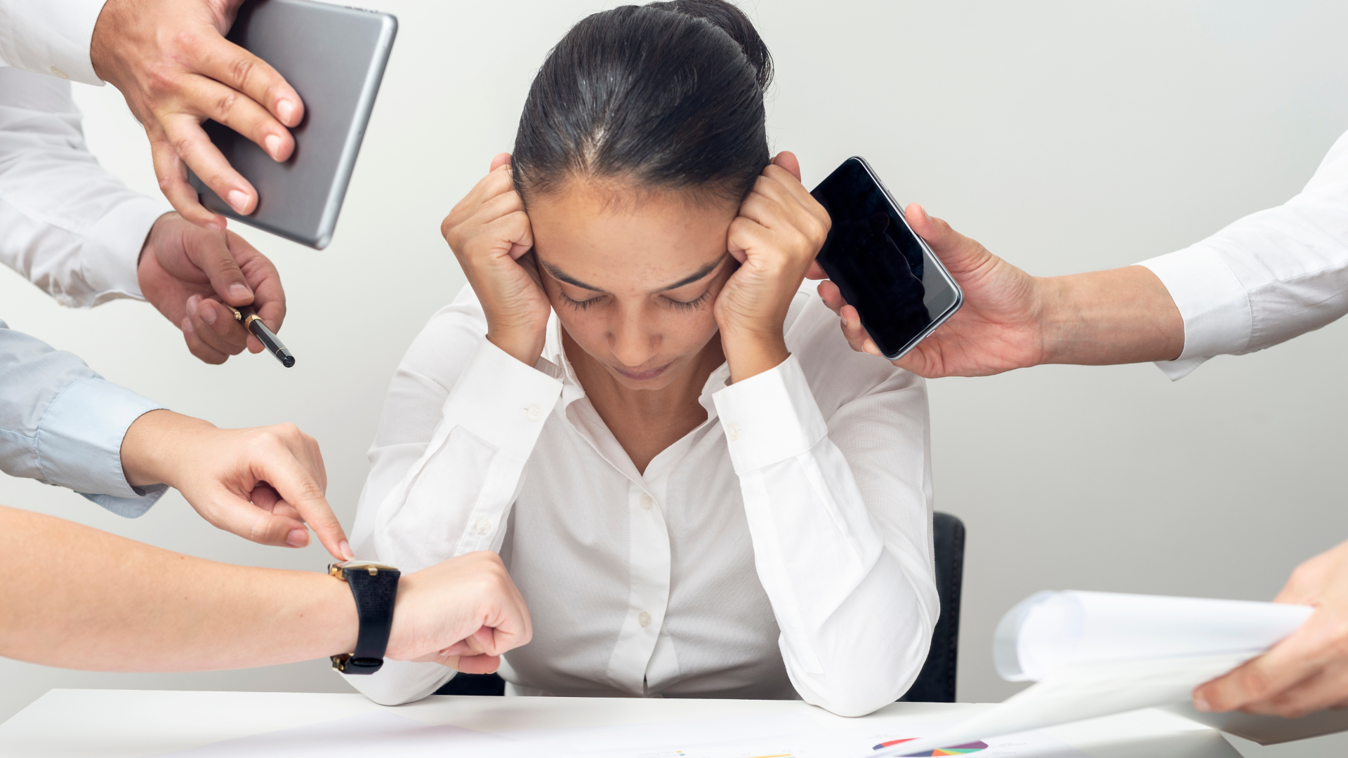 A woman with dark hair and a white shirt looks overwhelmed as multiple hands with devices and papers surround her, pointing or pressing on her wrist, head, and papers.