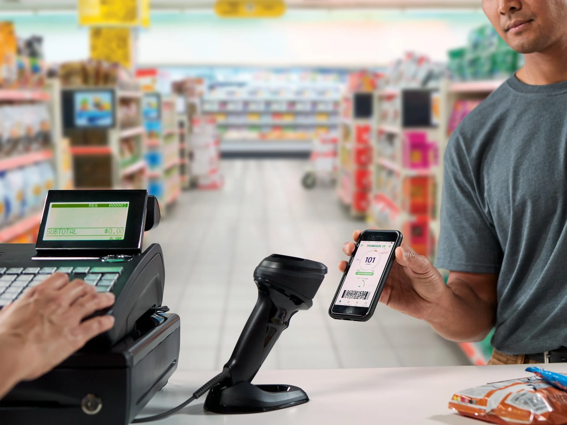 Persona usando un teléfono móvil con código QR en una caja de supermercado mientras realiza una compra.