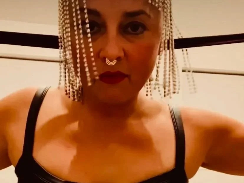 A flat lay of vintage sheet music, blank aged papers, pink flowers, a white cup of coffee, and a cream-colored fabric on a white surface.