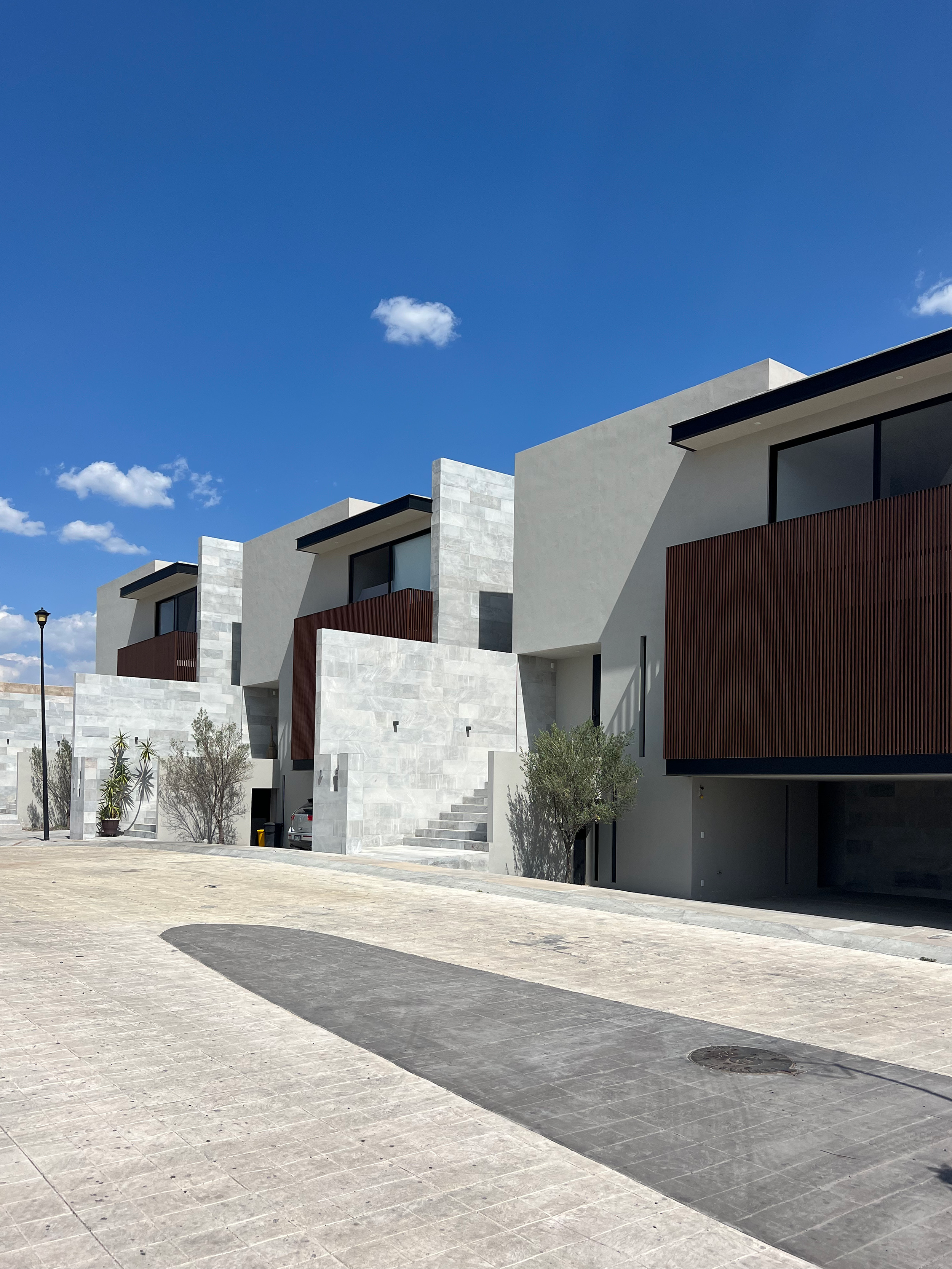 Conjunto de casas modernas con fachadas de piedra y madera, en un día soleado con cielo azul y pocas nubes.