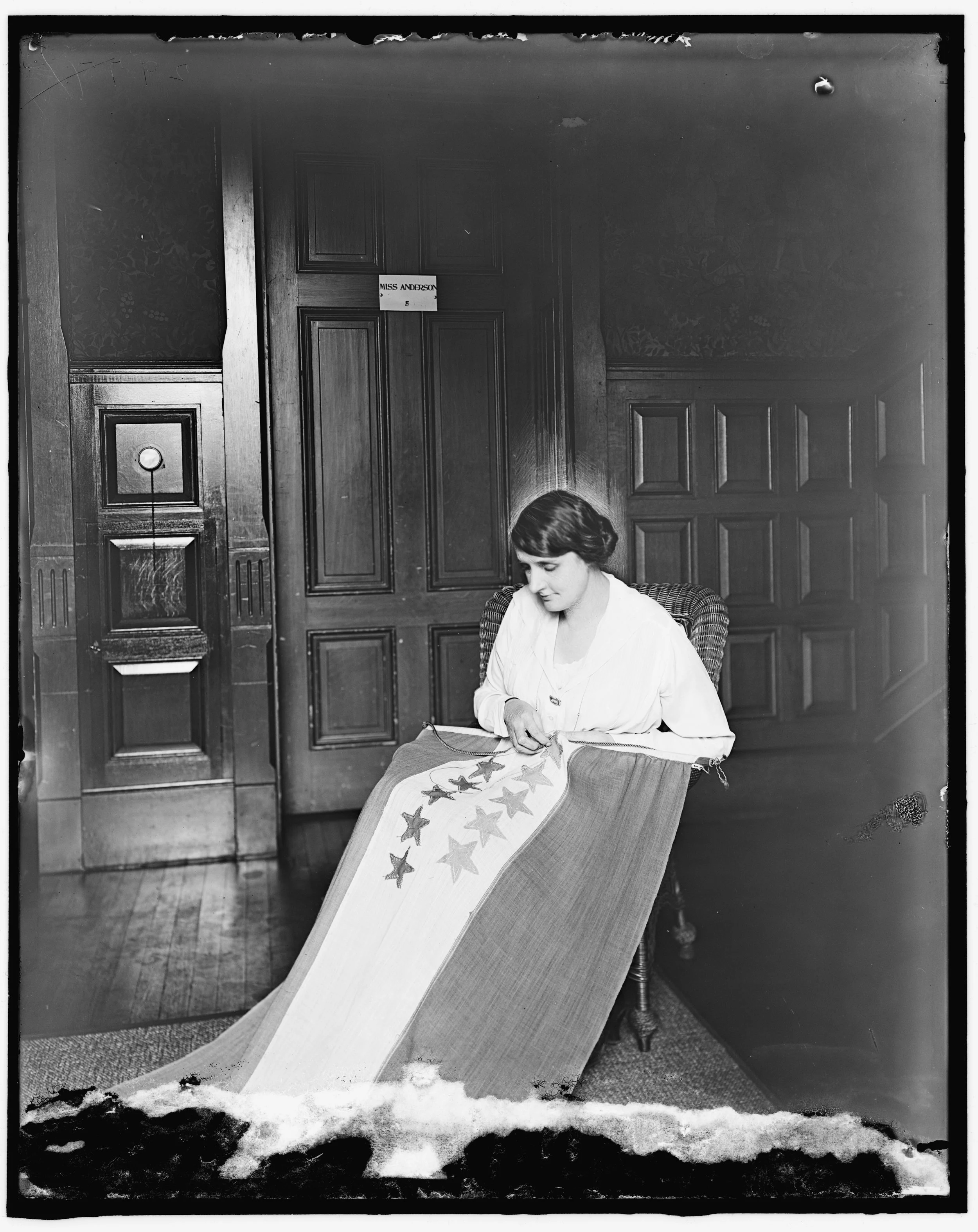 Woman sewing stars on suffrage banner
