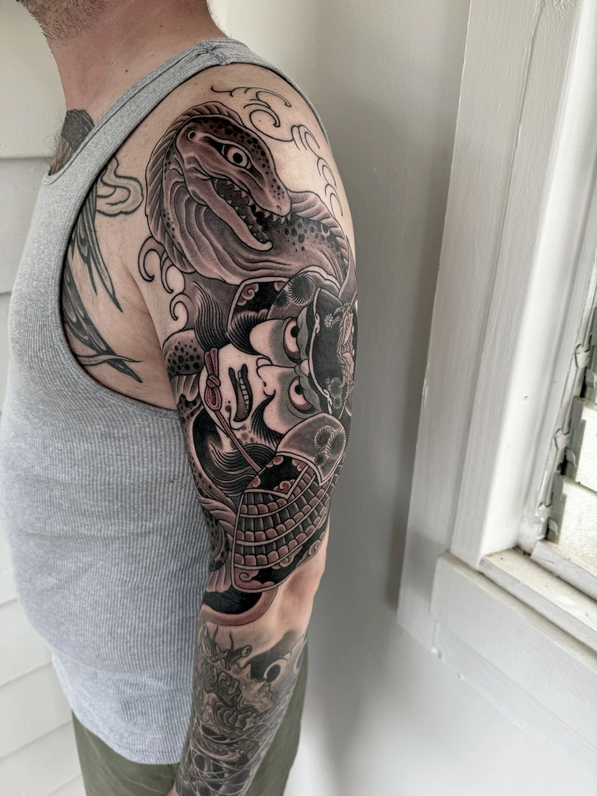 Tattoo of a T-Rex and skull on a person's upper arm.