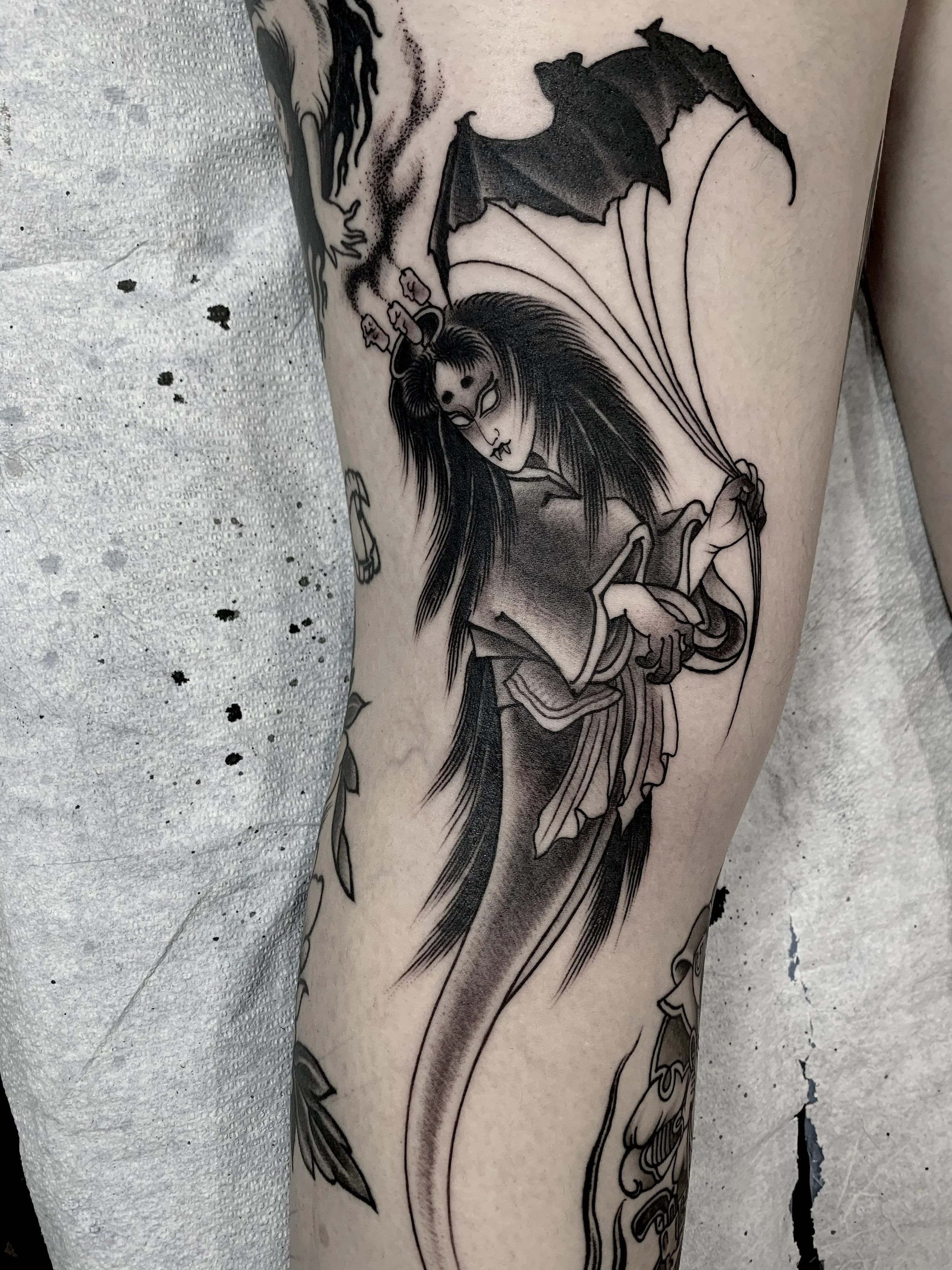 Tattoo of a woman with long hair, holding an umbrella, with floating candles above her head.