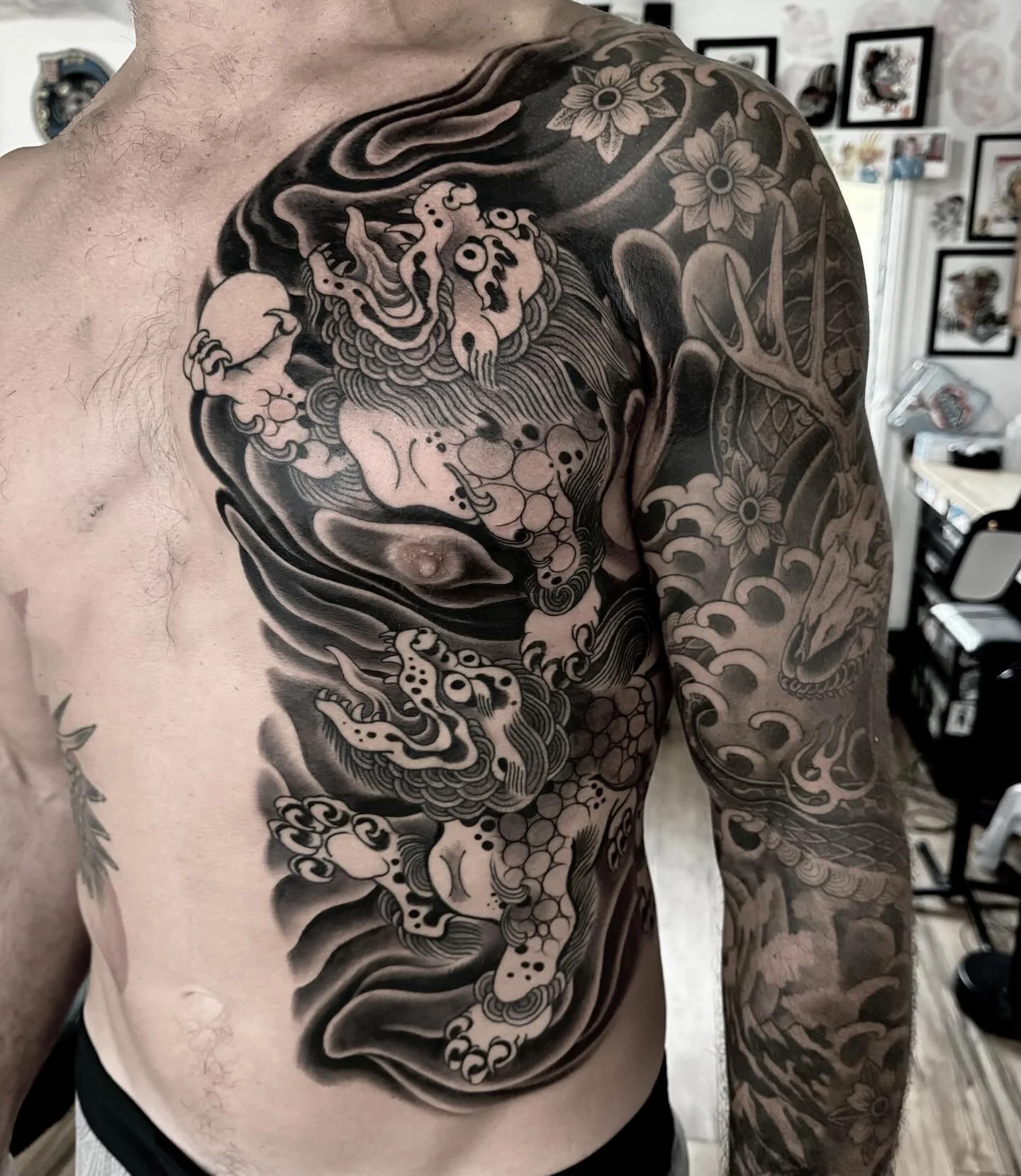 Black and gray traditional Japanese-style tattoo of a dragon on man's chest and arm.