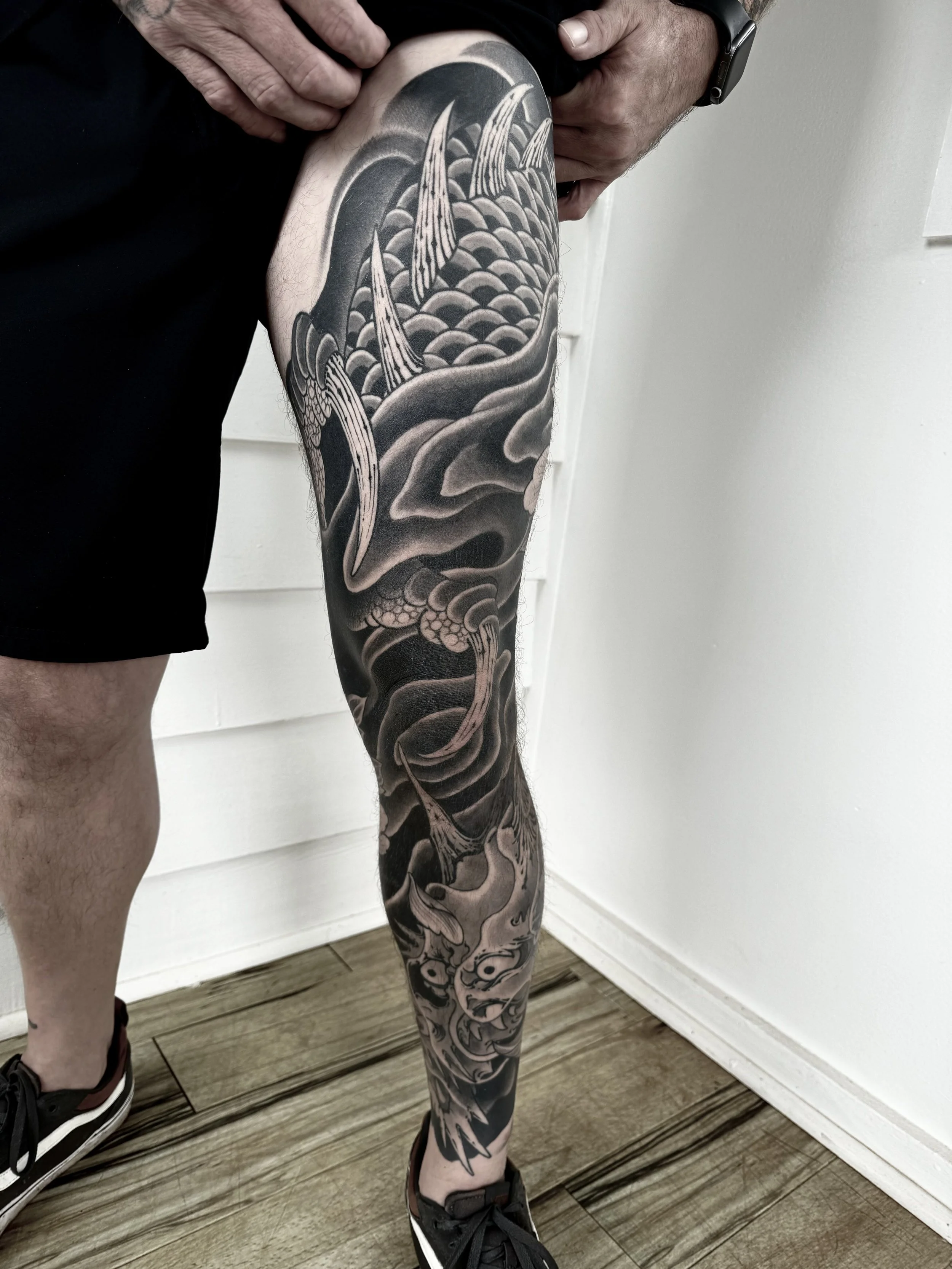 Black and gray Japanese-style dragon tattoo covering the person's entire leg from thigh to ankle.
