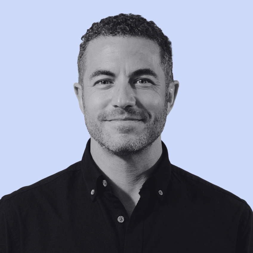 smiling man in black shirt with pale blue background