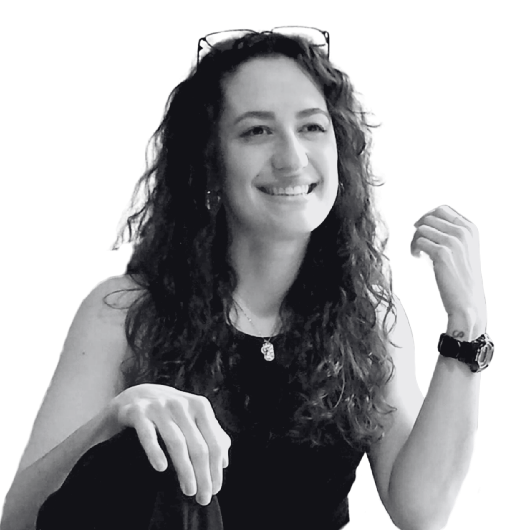 woman with curly hair and glasses on her head smiling and looking into the distance