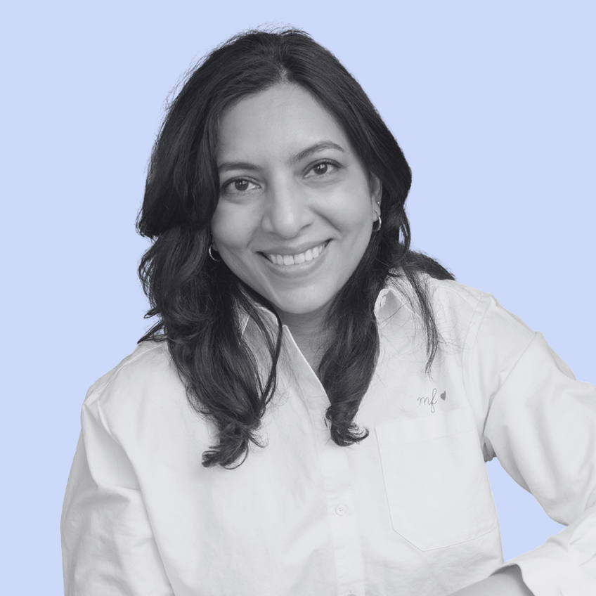 black and white photo of smiling woman wearing a white shirt on a pale blue background