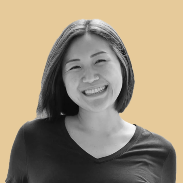 woman smiling with dark top on yellow background