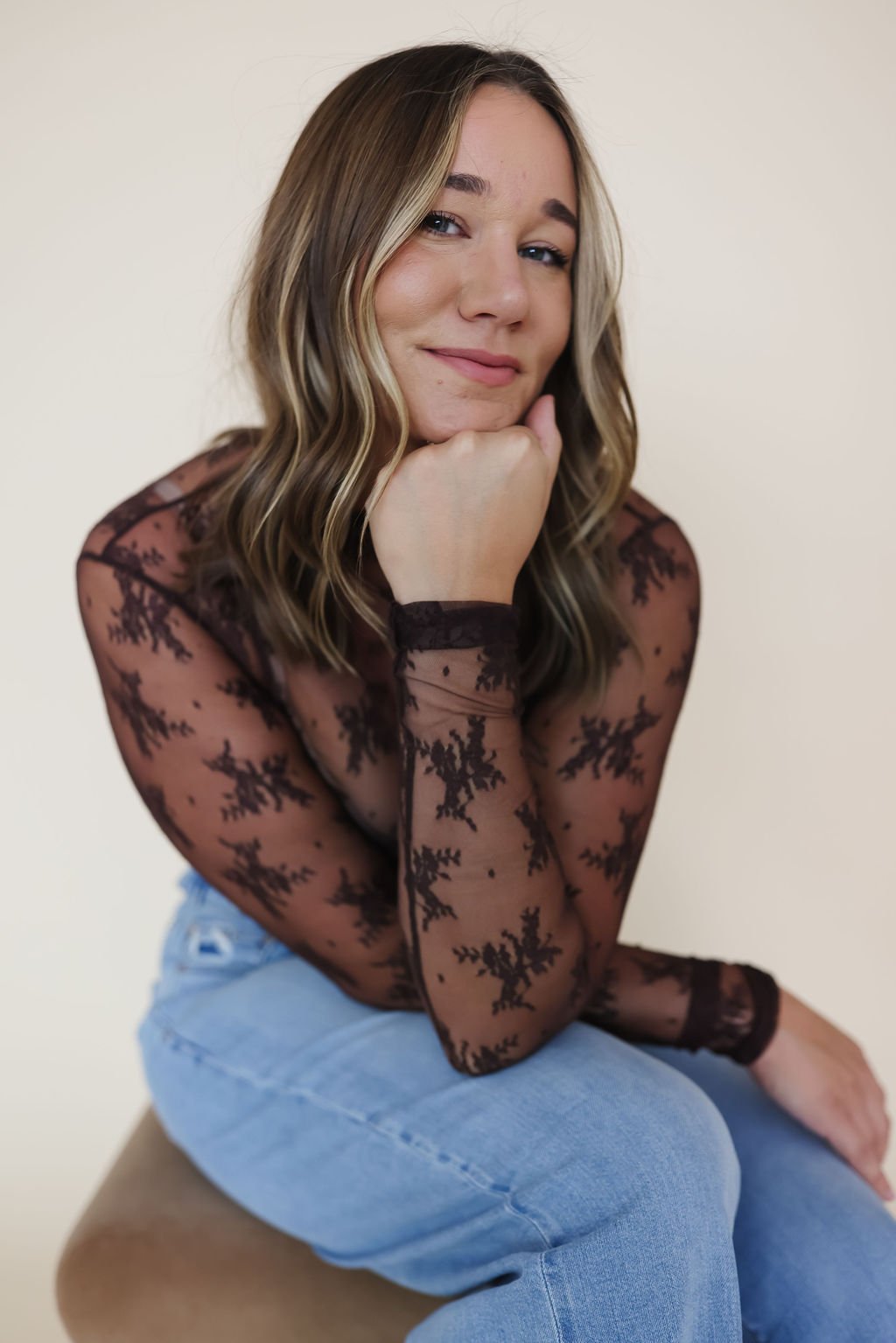 smiling woman resting her head on her hand and her elbow on her knee