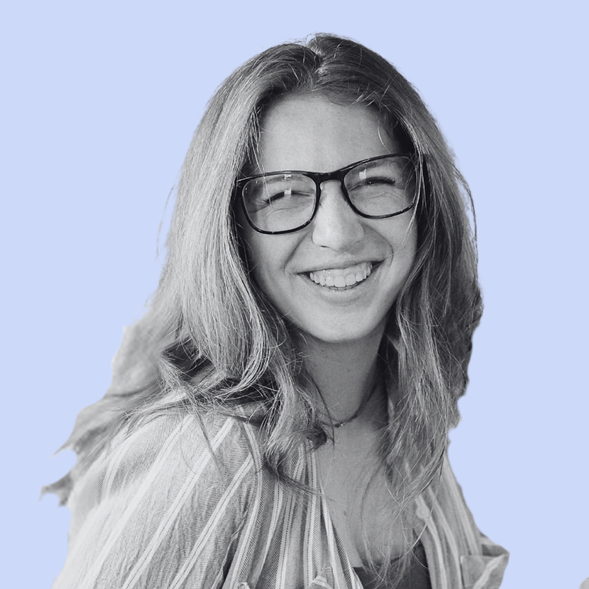 smiling woman wearing glasses looking over shoulder wearing striped shirt