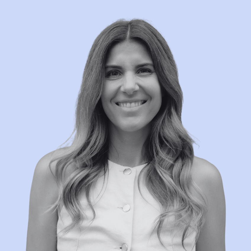 smiling woman with long wavy hair wearing a buttoned white vest
