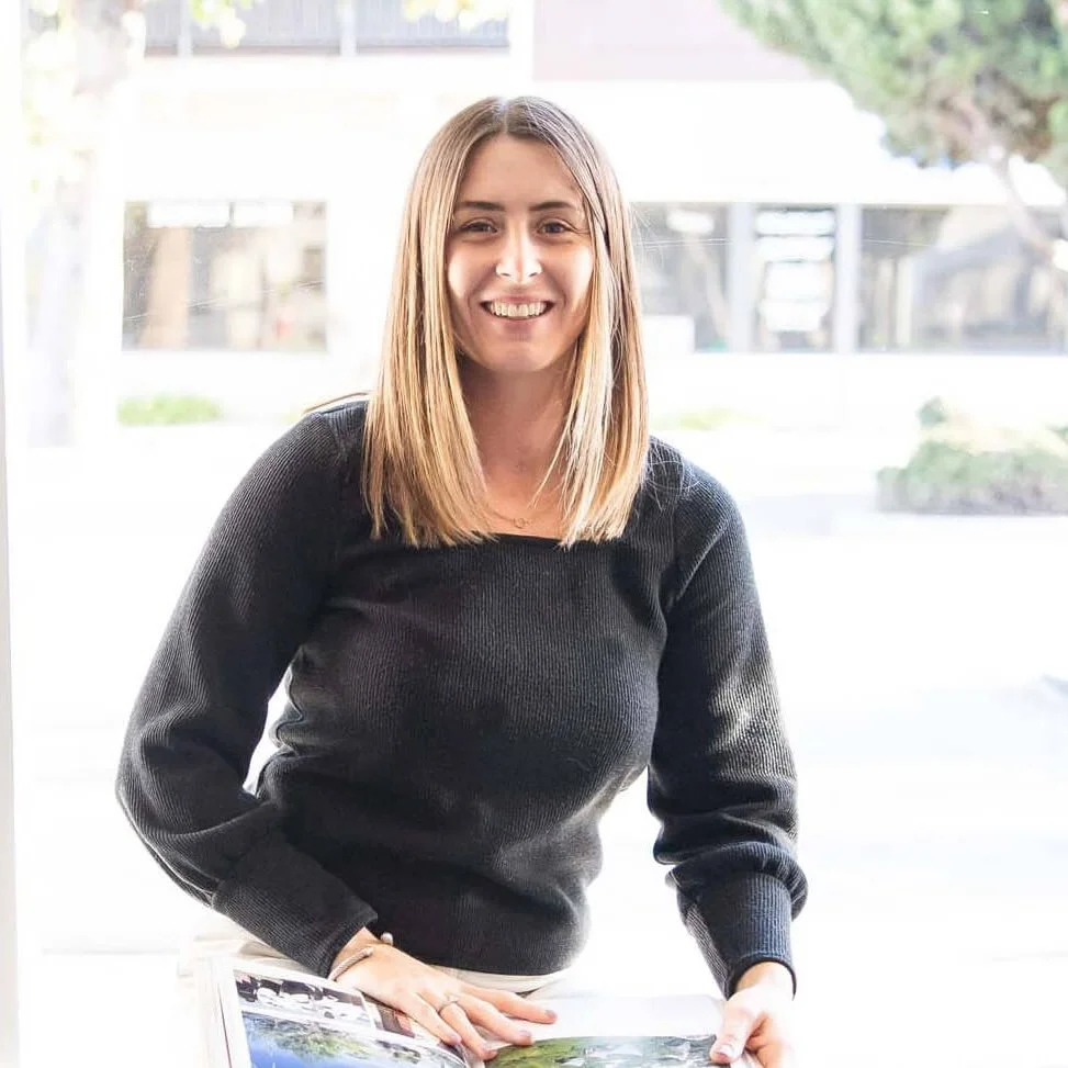 A smiling woman with straight hair holding a book