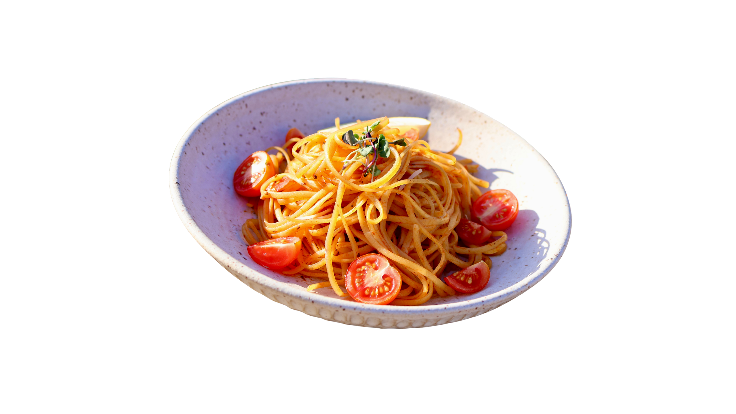 A white, speckled ceramic plate with spaghetti pasta, cherry tomatoes, and microgreens on top.