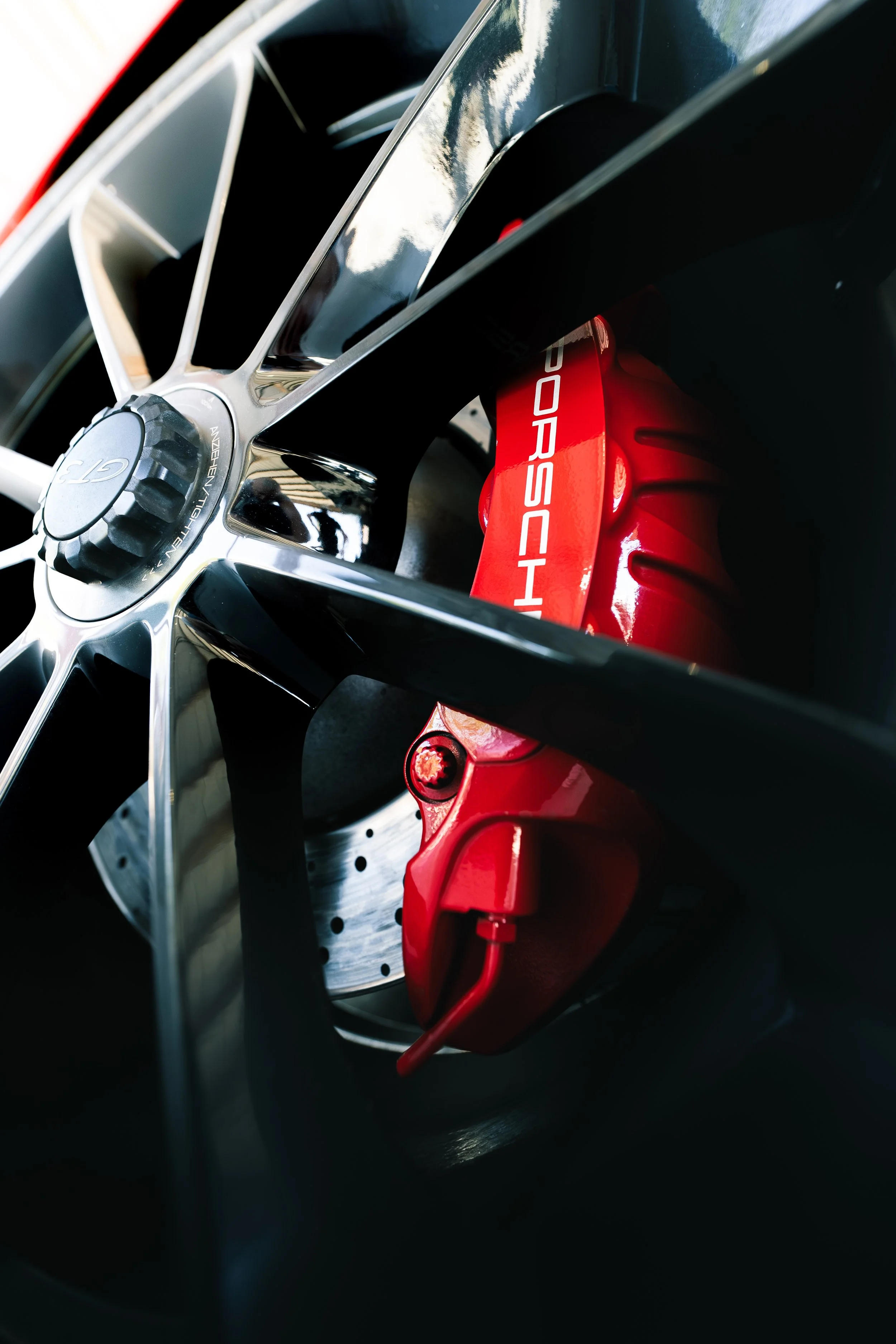 Close-up of a car wheel with a chrome rim and a red Porsche brake caliper.