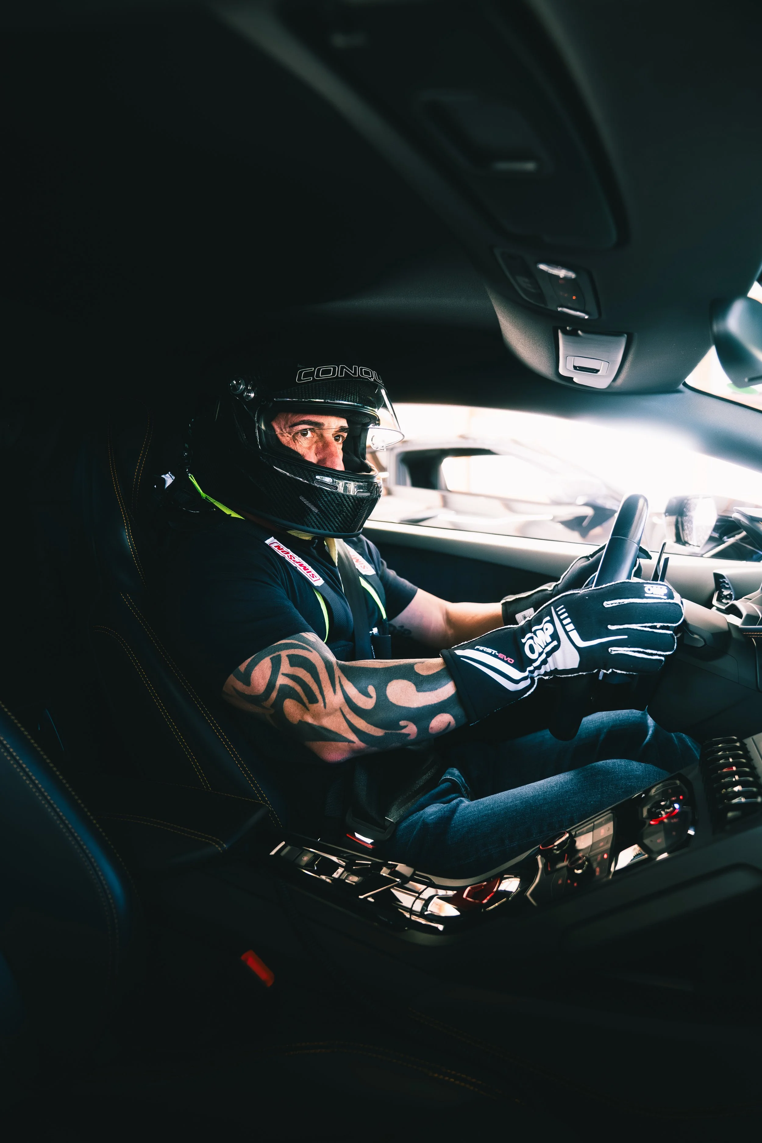 A race car driver sitting in a modern car, wearing a racing helmet and gloves, ready to drive.