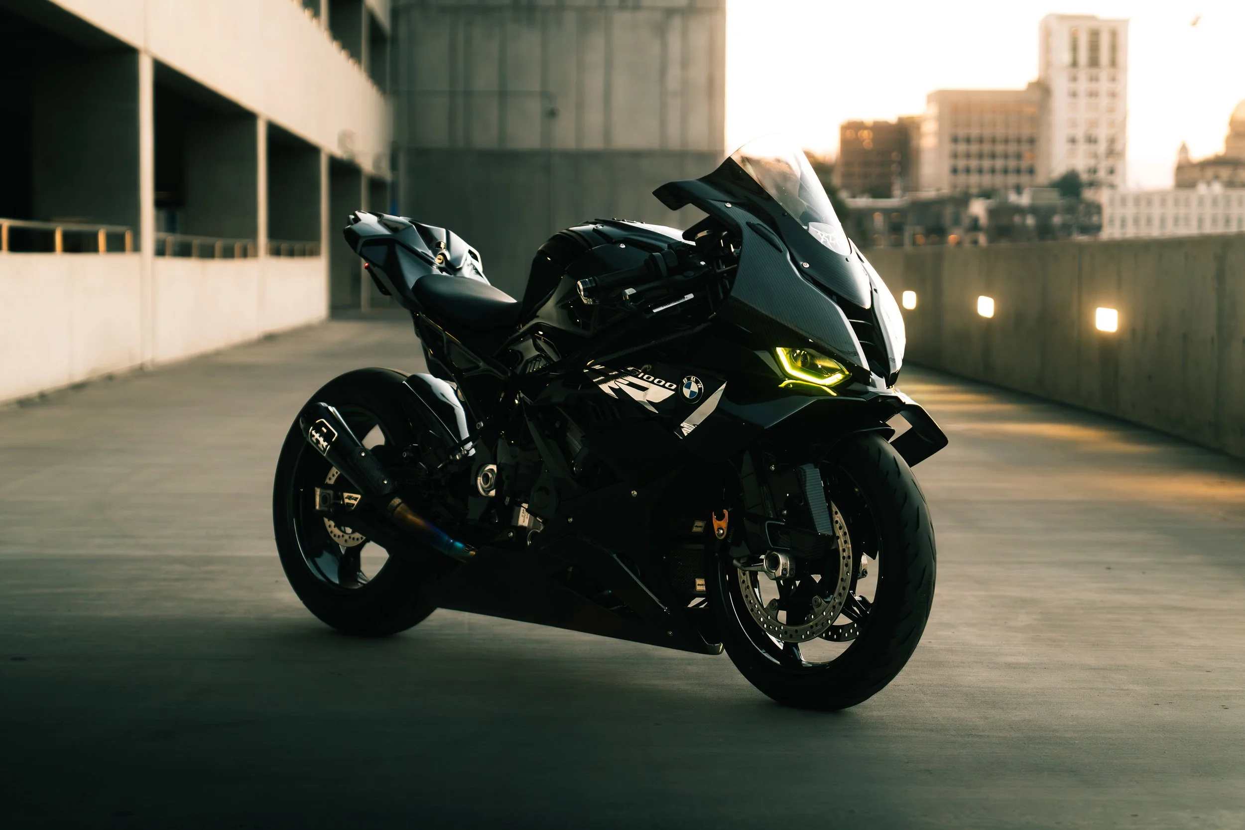 A black BMW motorcycle parked in an urban parking lot at sunset.